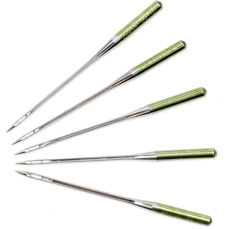 Five silver sewing machine needles with green tops and visible markings.