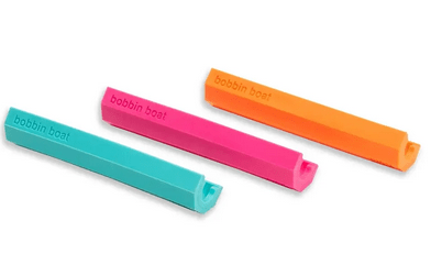 Three colorful bobbin holders for thread organization.