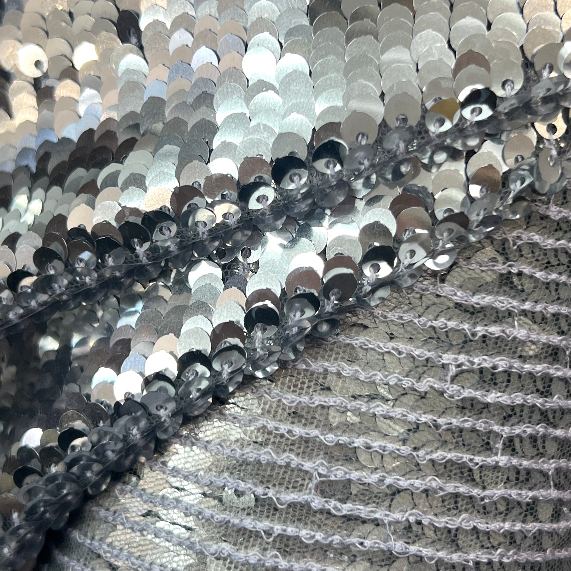 Close-up of silver sequin fabric with a textured background