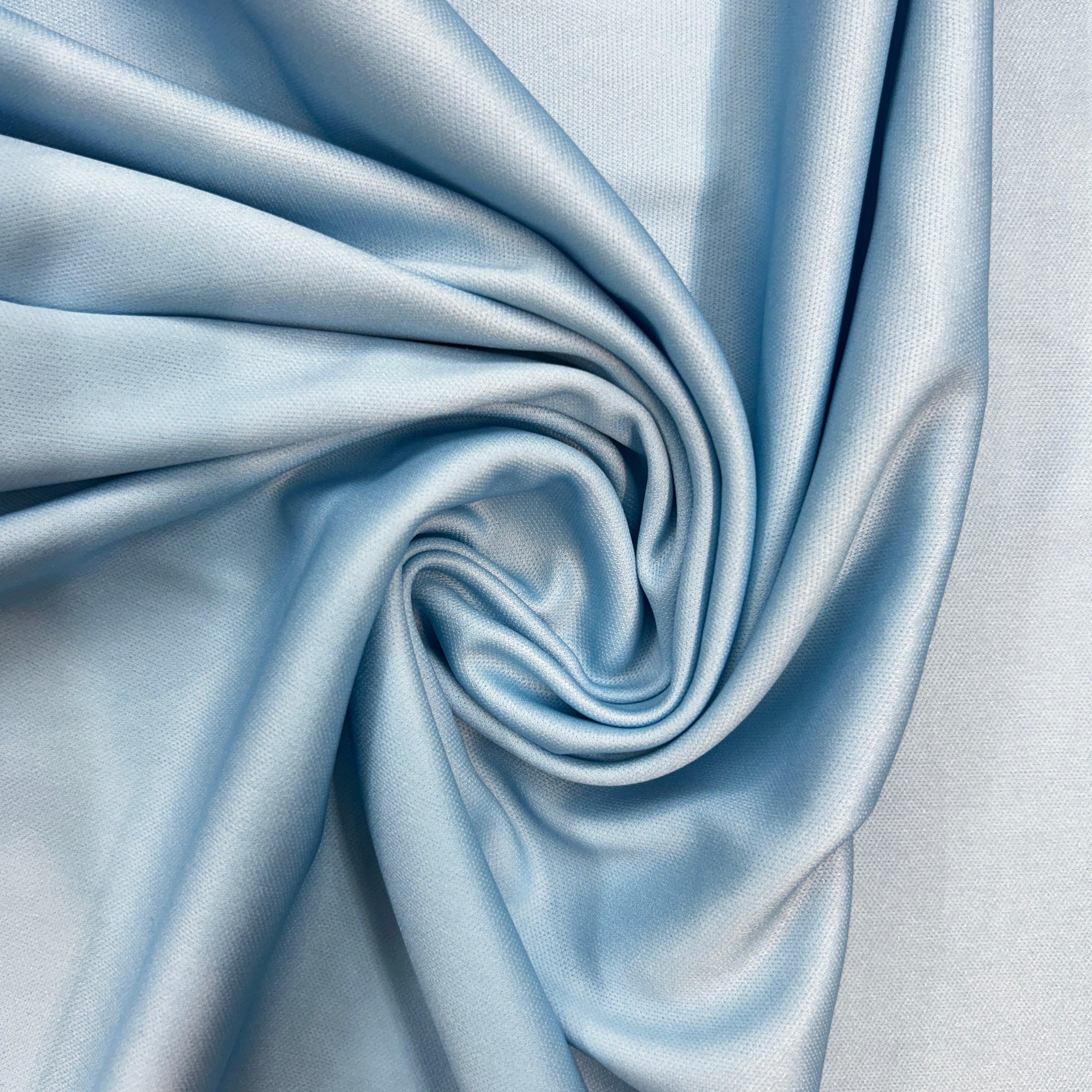 Close-up of light blue fabric with folds on a light gray background