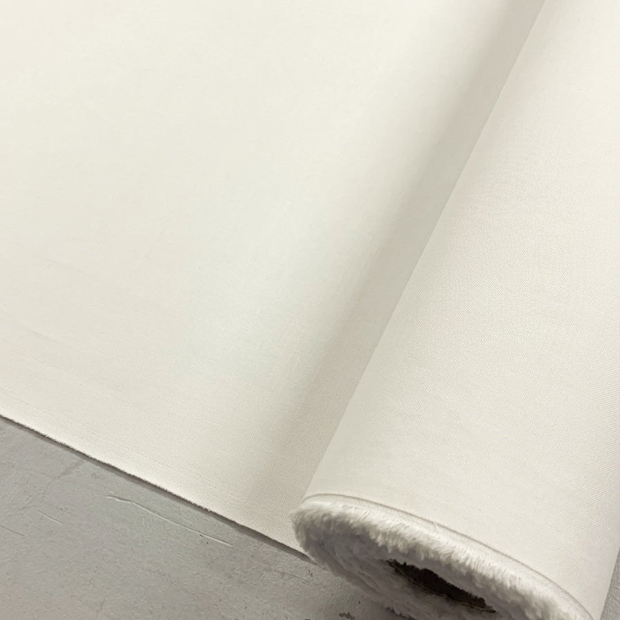 A close-up of a white roll of fabric or material, partially unrolled, resting on a gray surface.