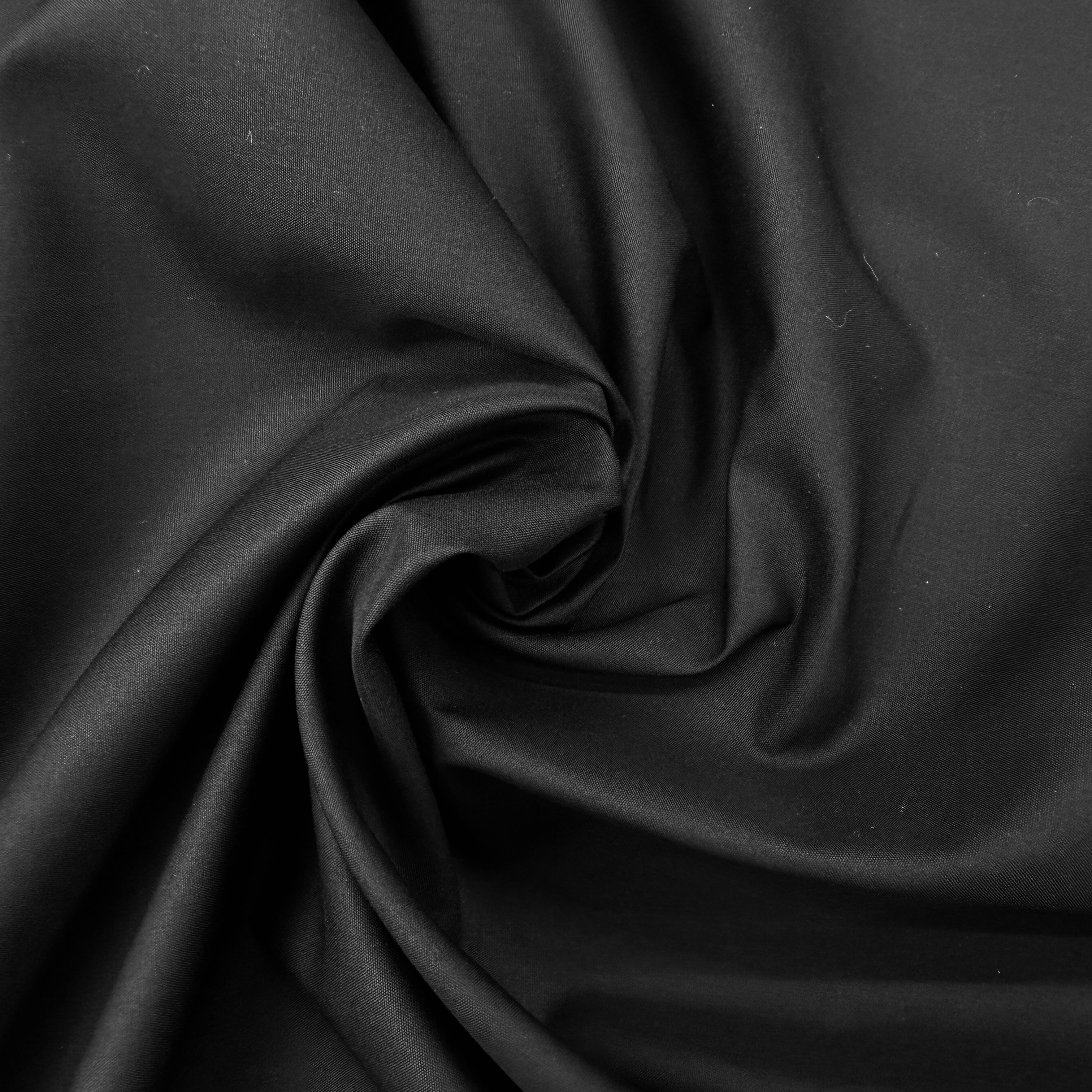A close-up of draped black fabric with soft folds and a smooth texture.