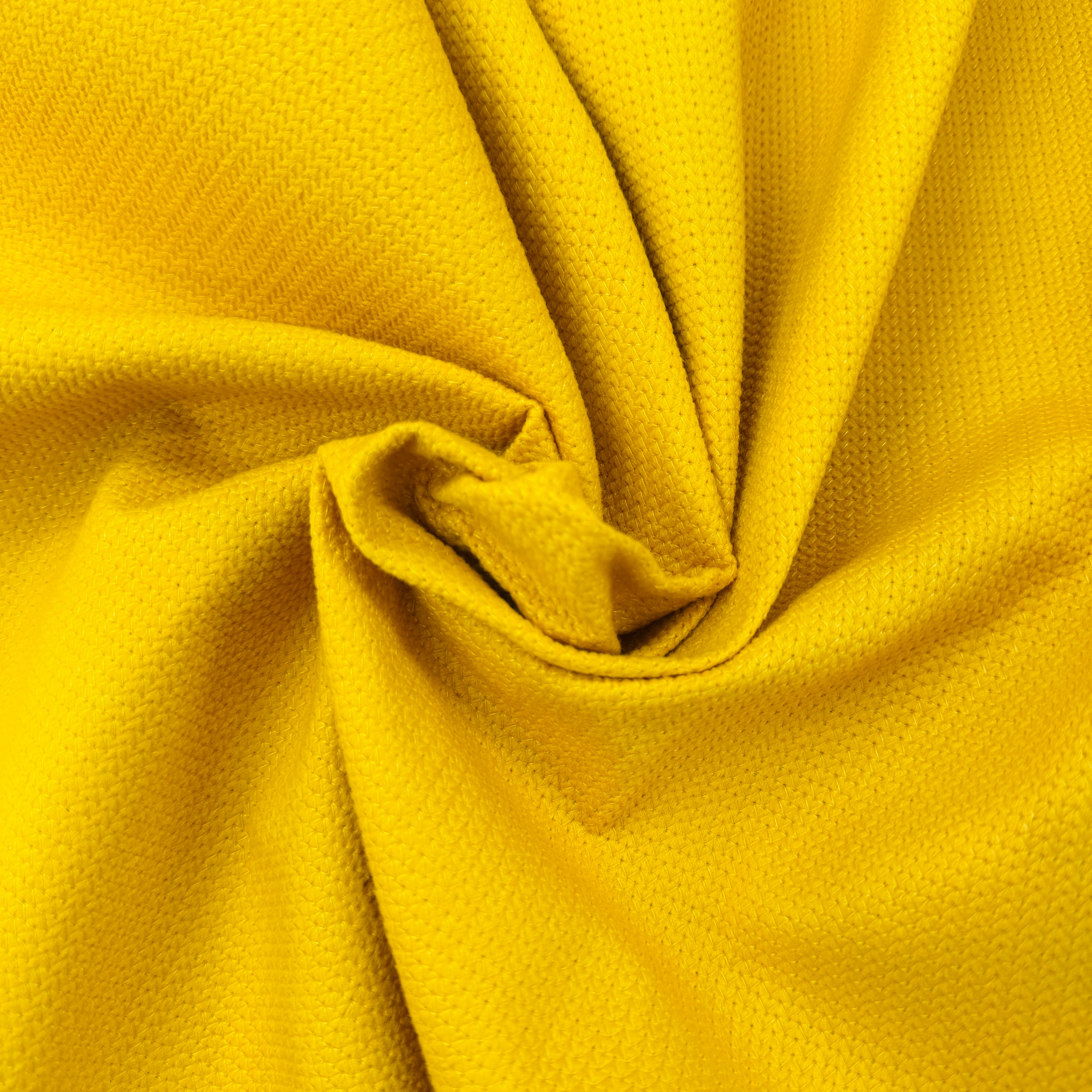 A close-up of bright yellow textured fabric with a gathered swirl in the center, showing the material's fine woven pattern.