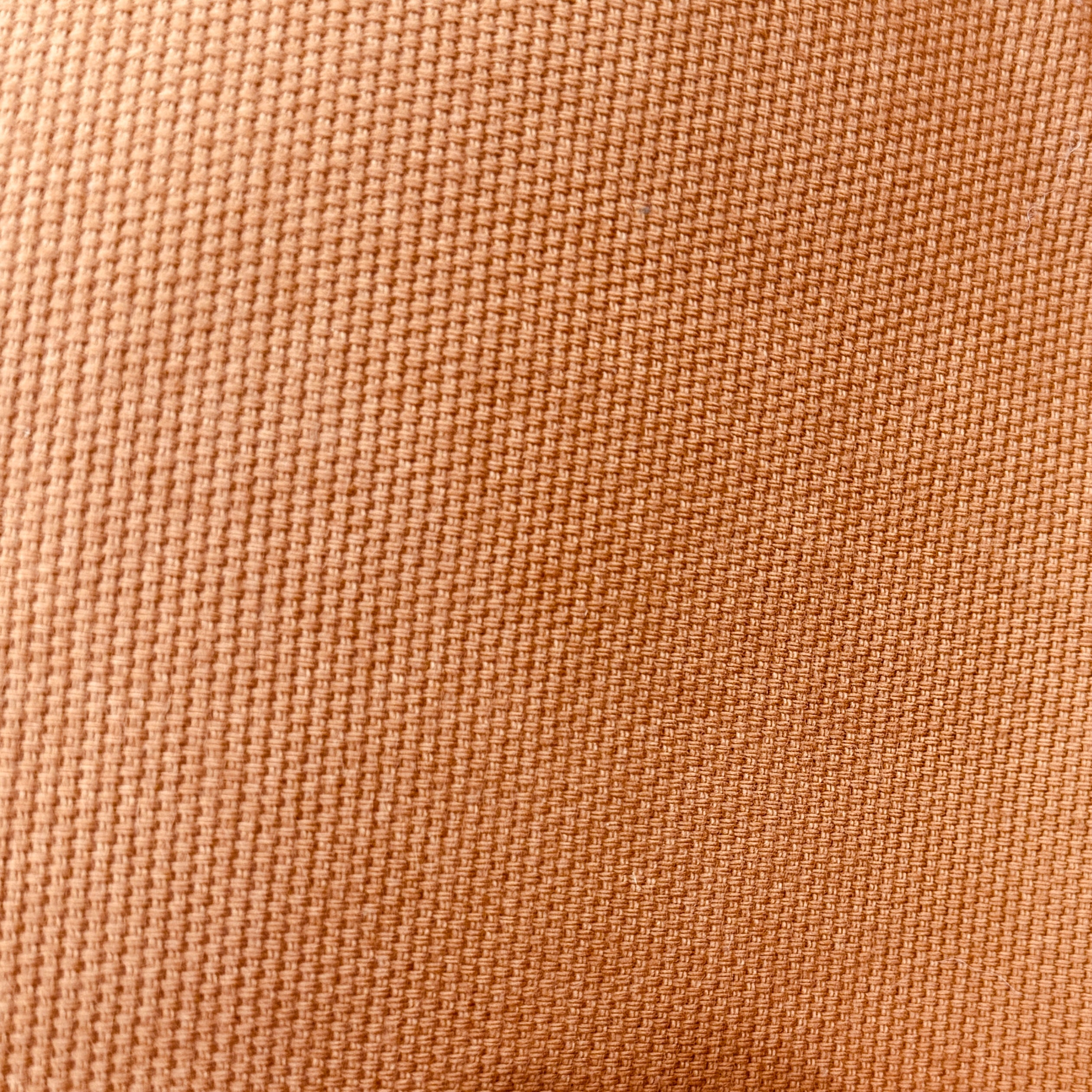 A close-up of a woven fabric texture in a warm tan or camel color, showing the detailed weave pattern.