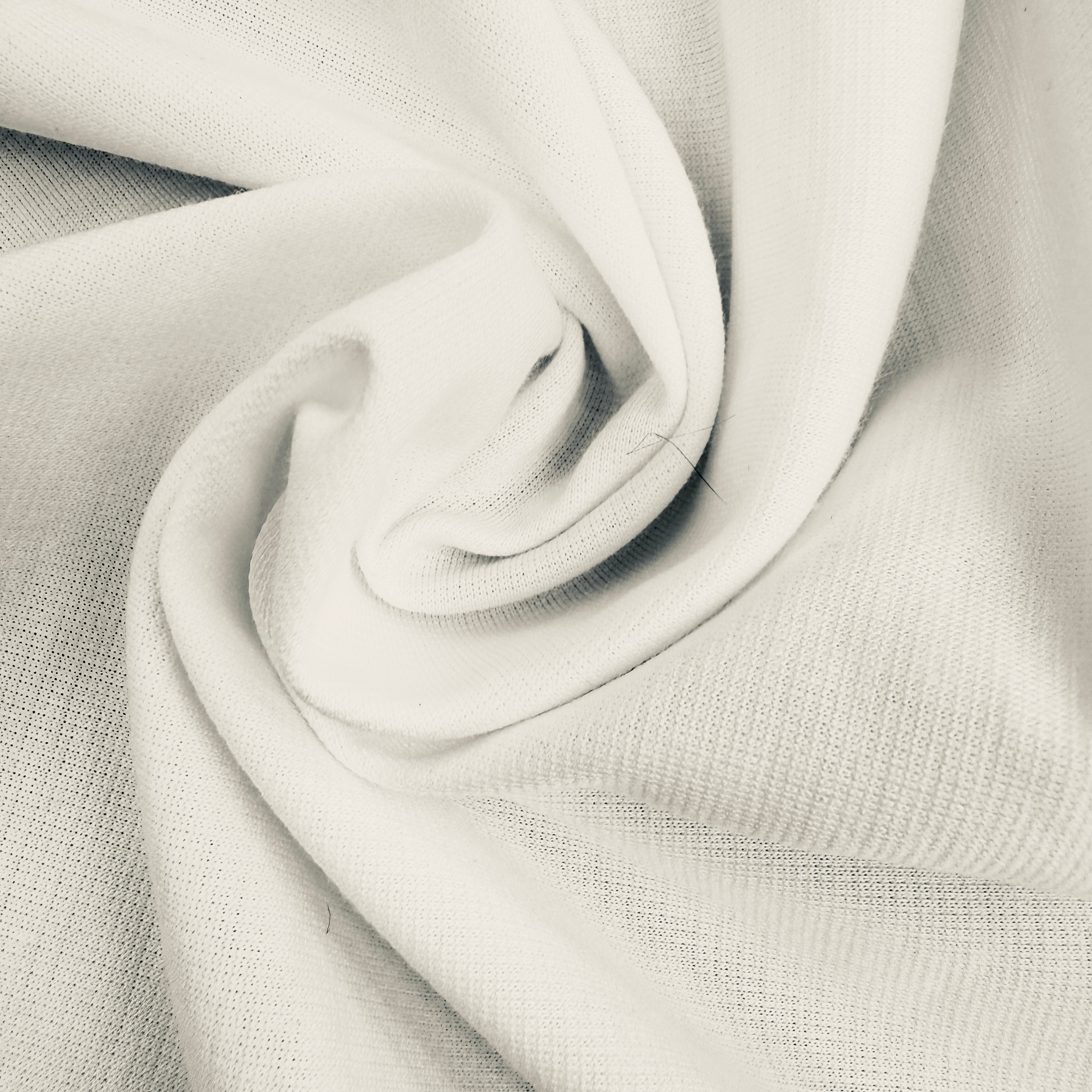 A close-up of light off-white woven fabric arranged in a spiral drape, showing the texture and material detail.