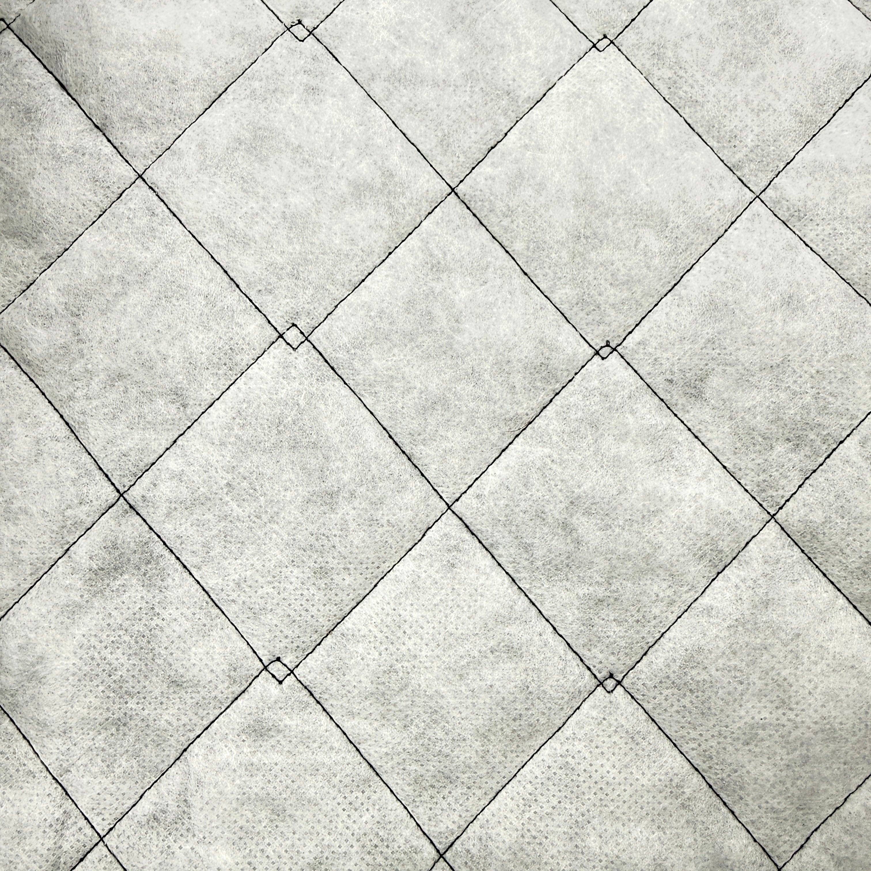 A close-up of a textured fabric or wallpaper pattern featuring a gray and white diamond lattice design with black stitched outlines.