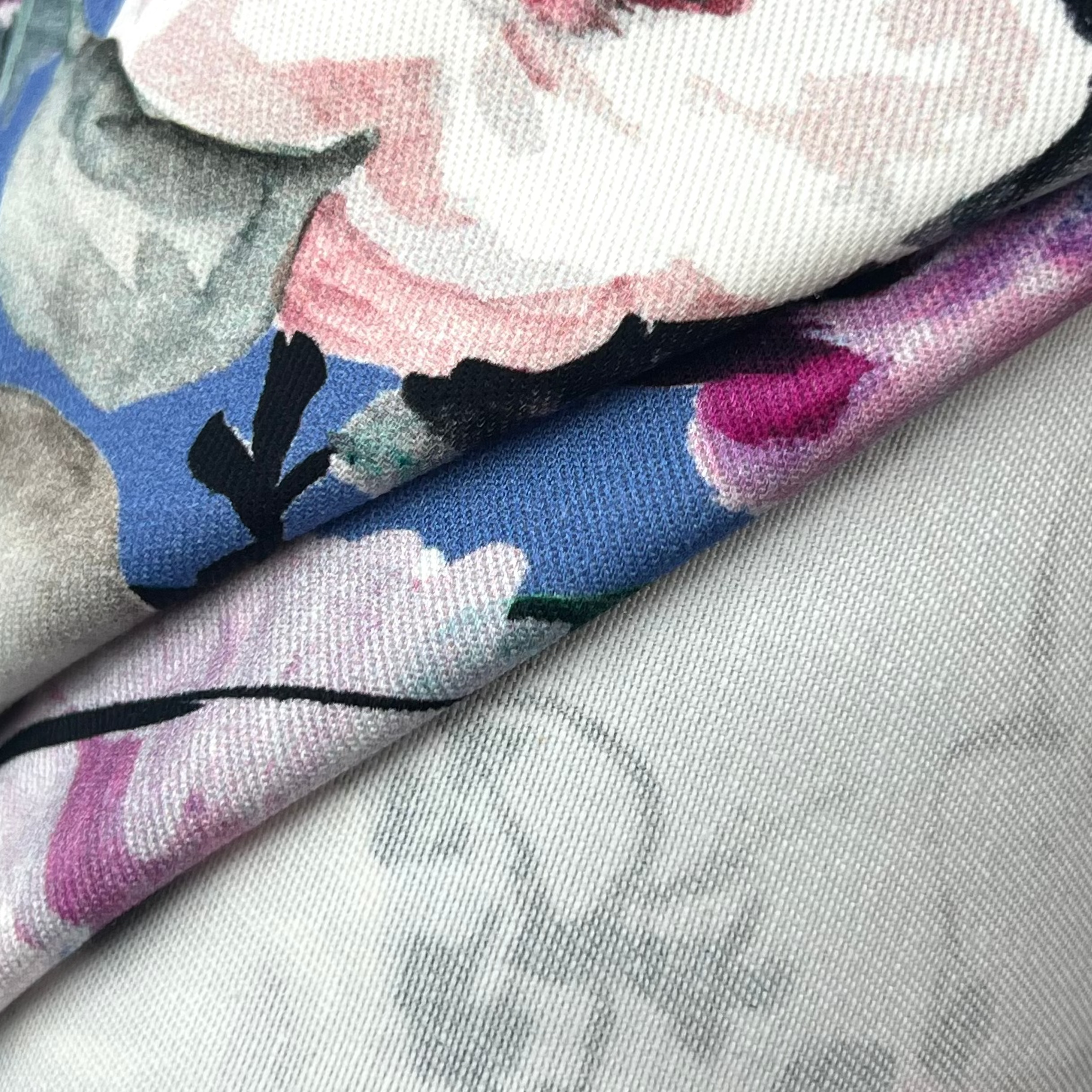 Close-up of blue floral printed cotton twill fabric showing diagonal weave and pink flower pattern.