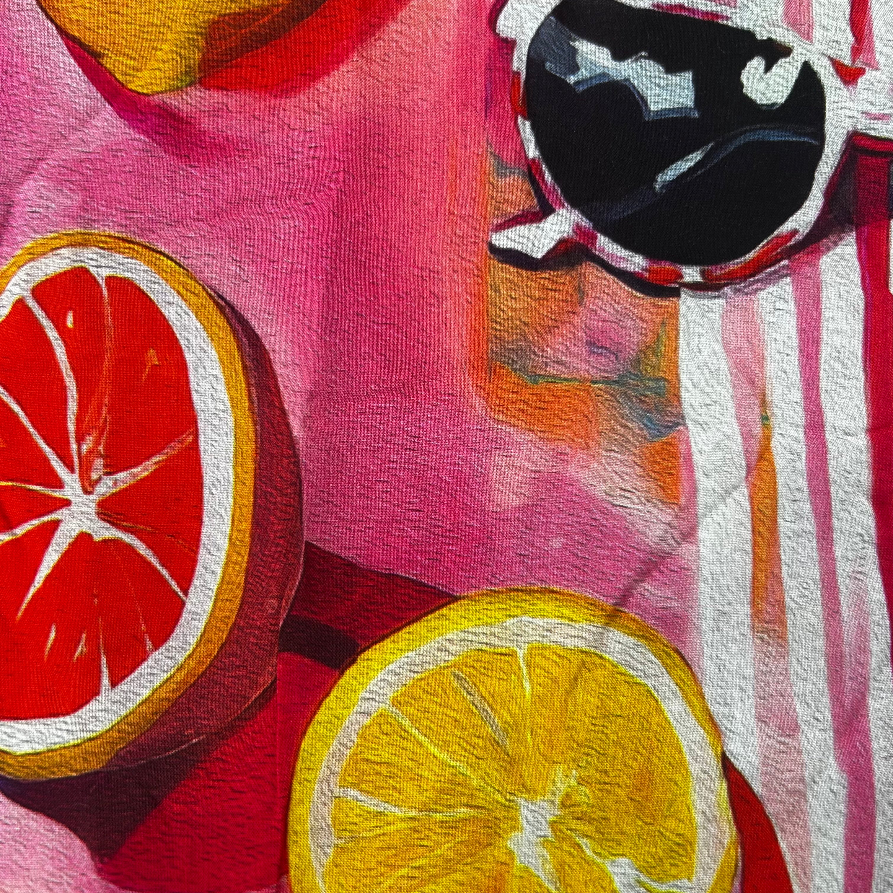Close-up of sliced oranges on a pink background with a black and white patterned object.