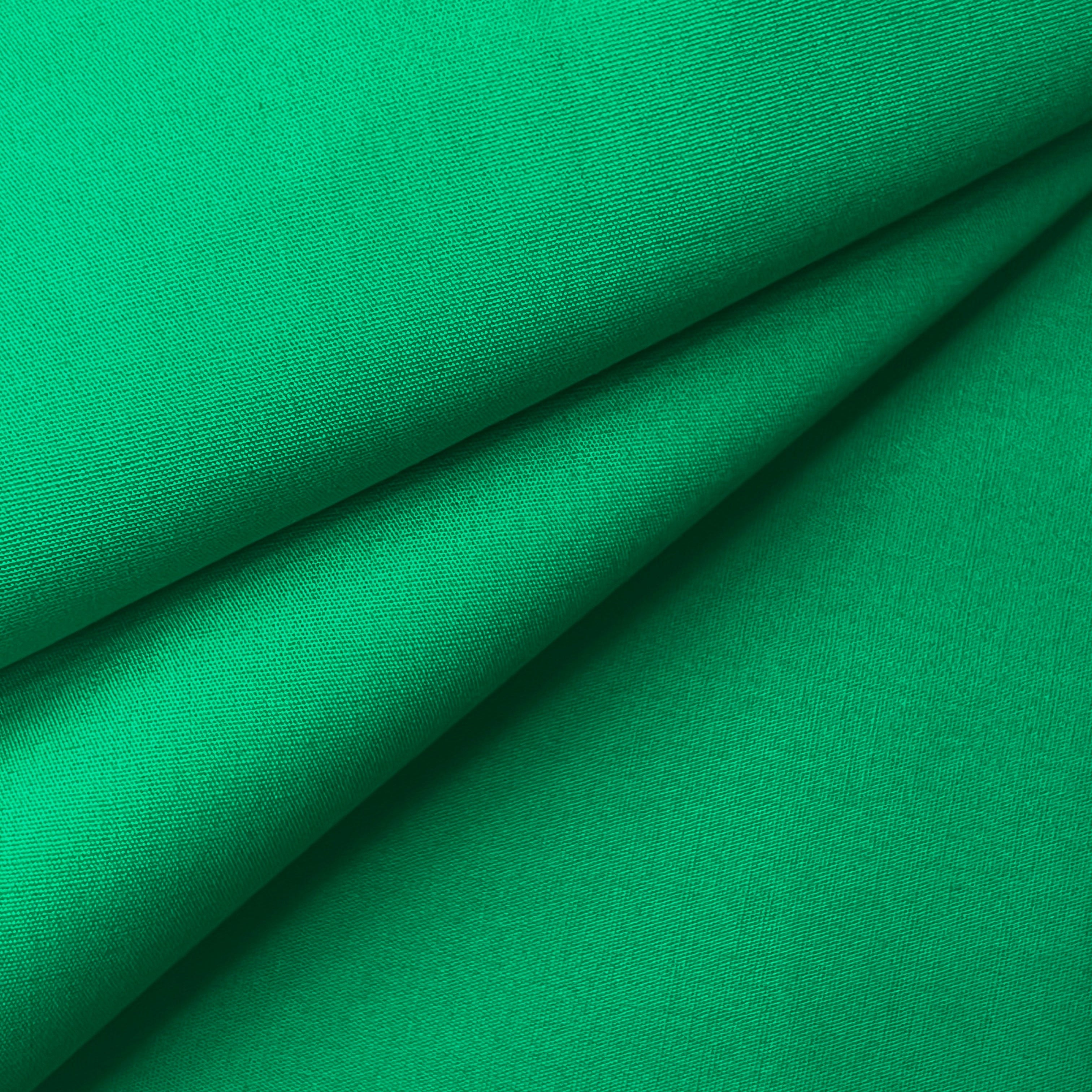 Close-up of green 100% cotton poplin plain weave fabric with soft folds.