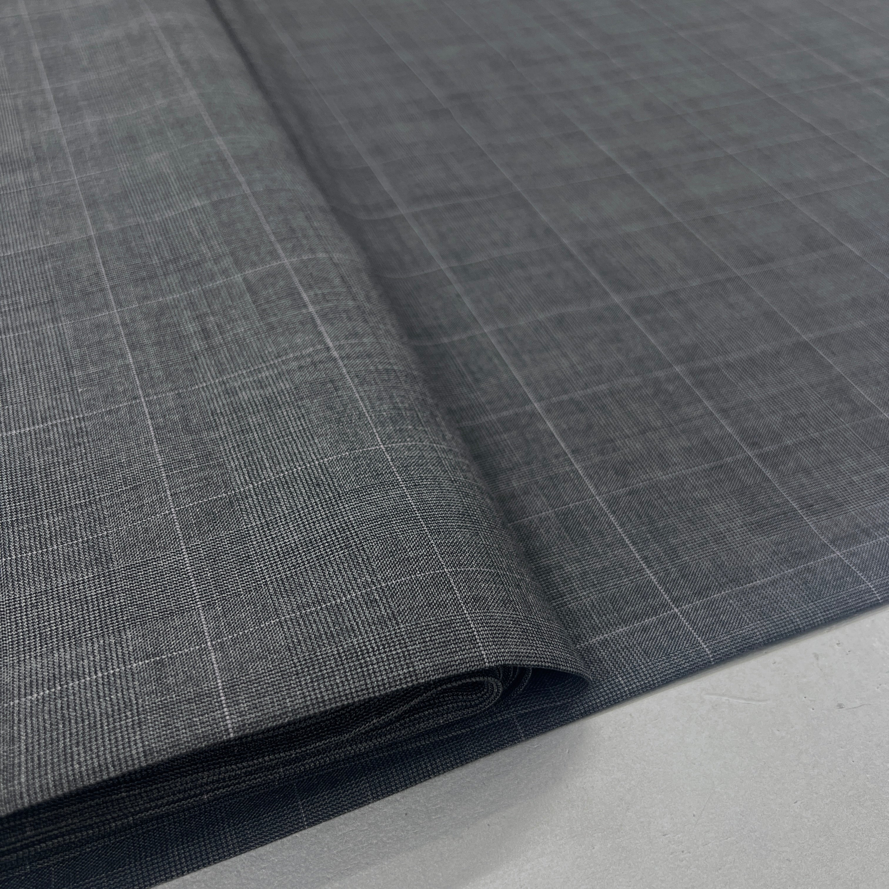 A close-up of dark gray fabric with a subtle white windowpane plaid pattern, folded over to show its texture and weight.