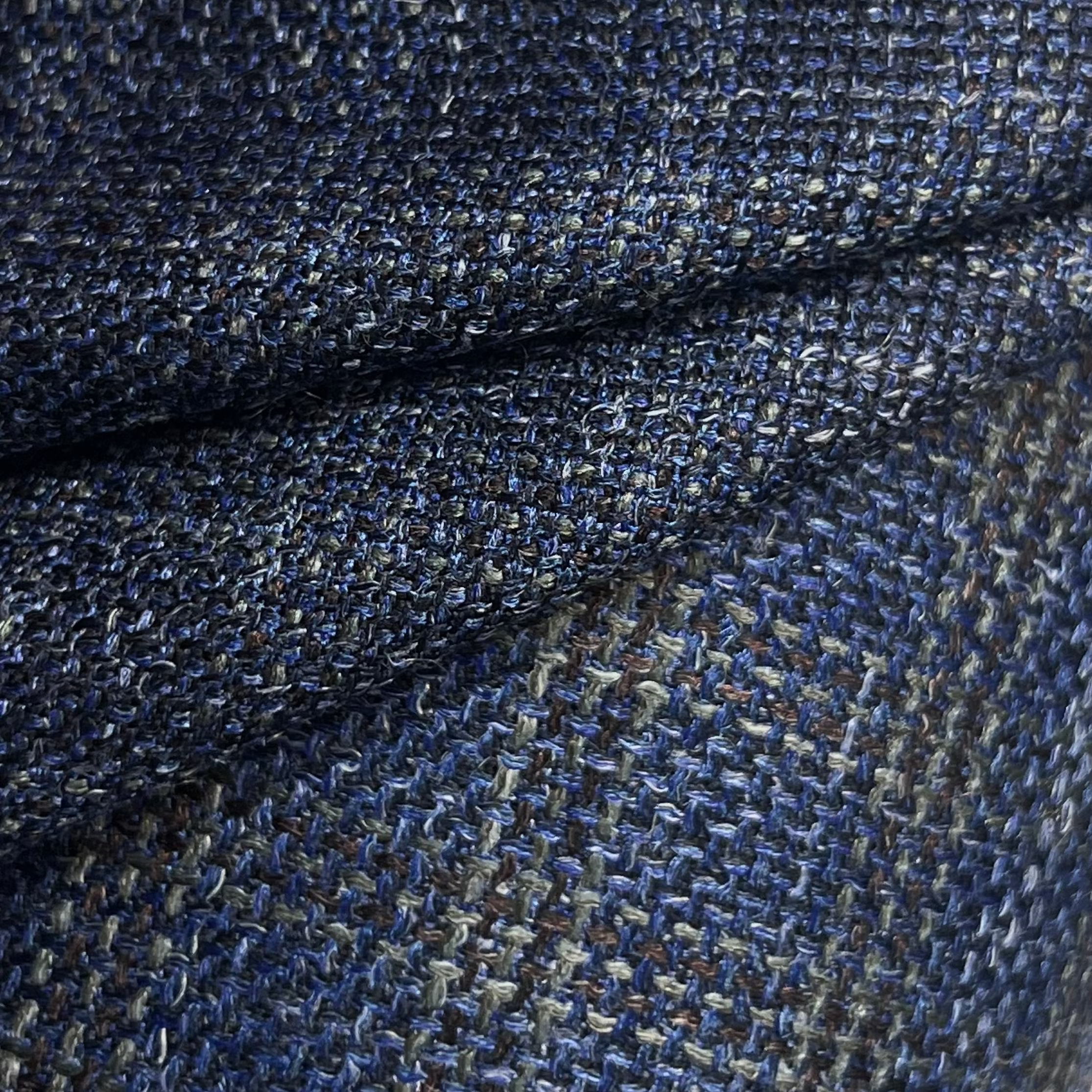 Close-up of dark blue virgin wool and silk tweed fabric with a textured, multi-tonal weave.