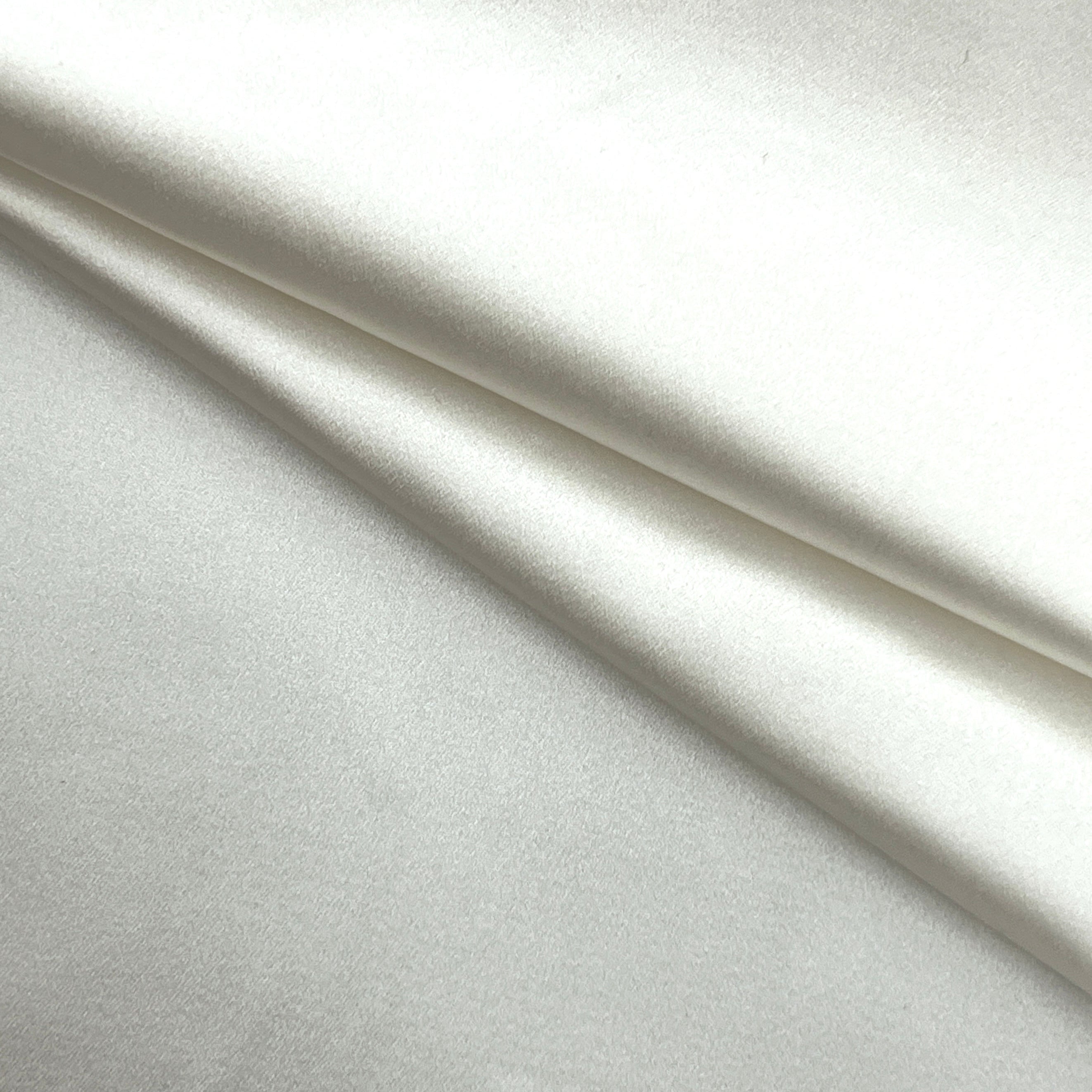 A close-up of draped white fabric with soft folds and a smooth texture.