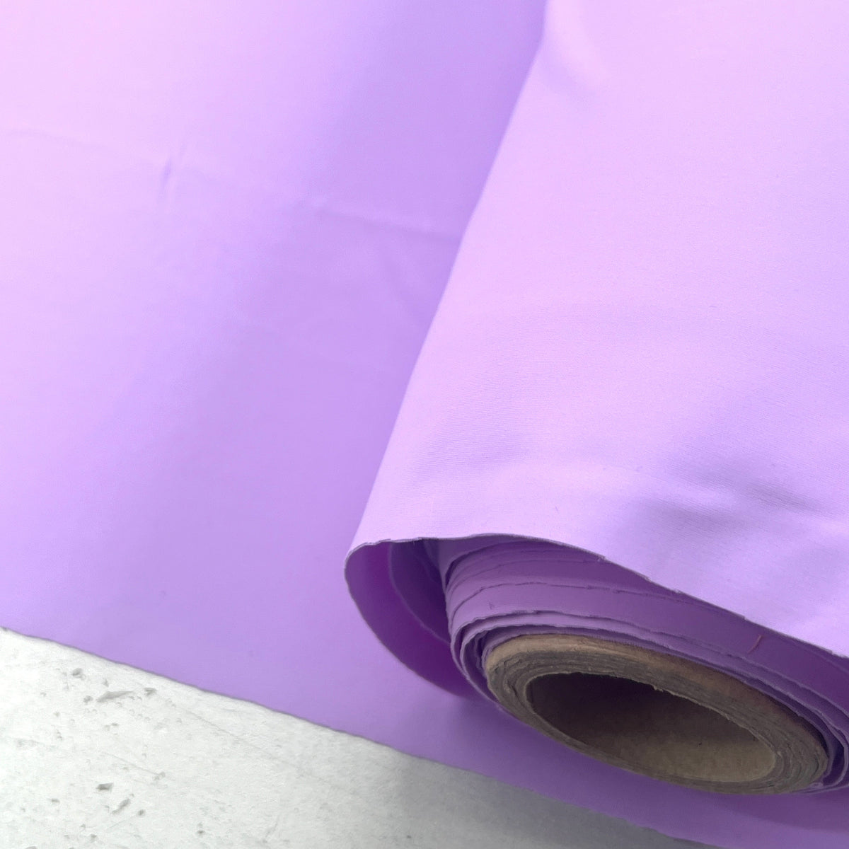 A roll of light purple/lavender vinyl or plastic sheeting material partially unrolled, showing its smooth surface and cardboard core.