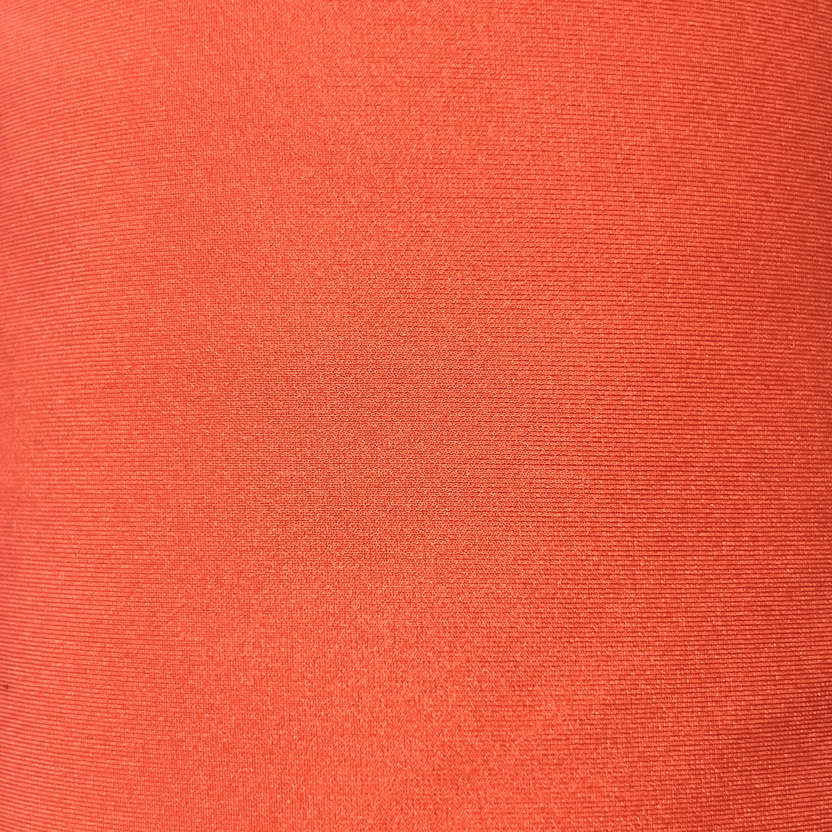 A close-up of a textured fabric in a solid coral orange color.