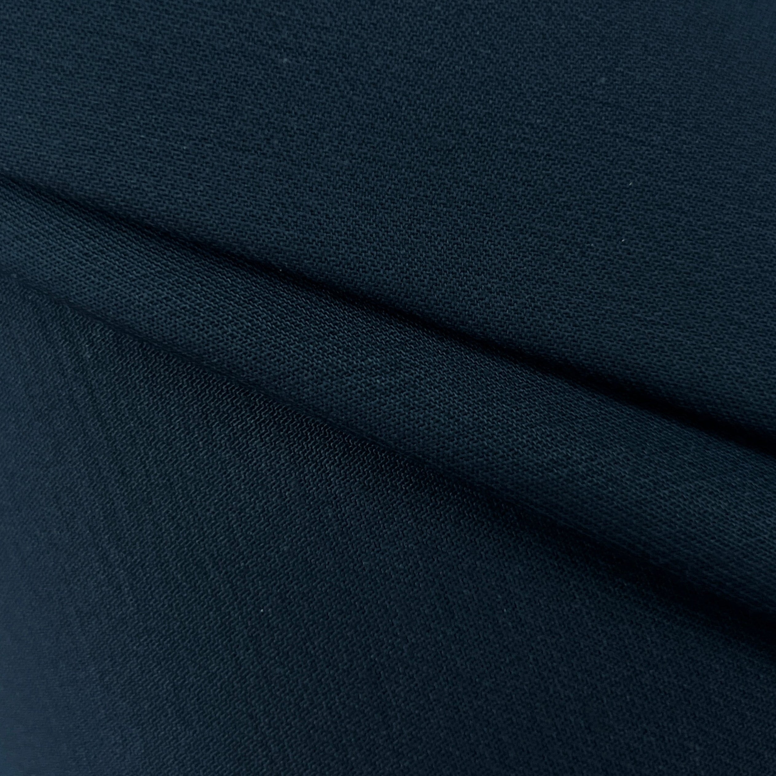 A close-up of dark navy blue fabric with a visible fold showing its texture.