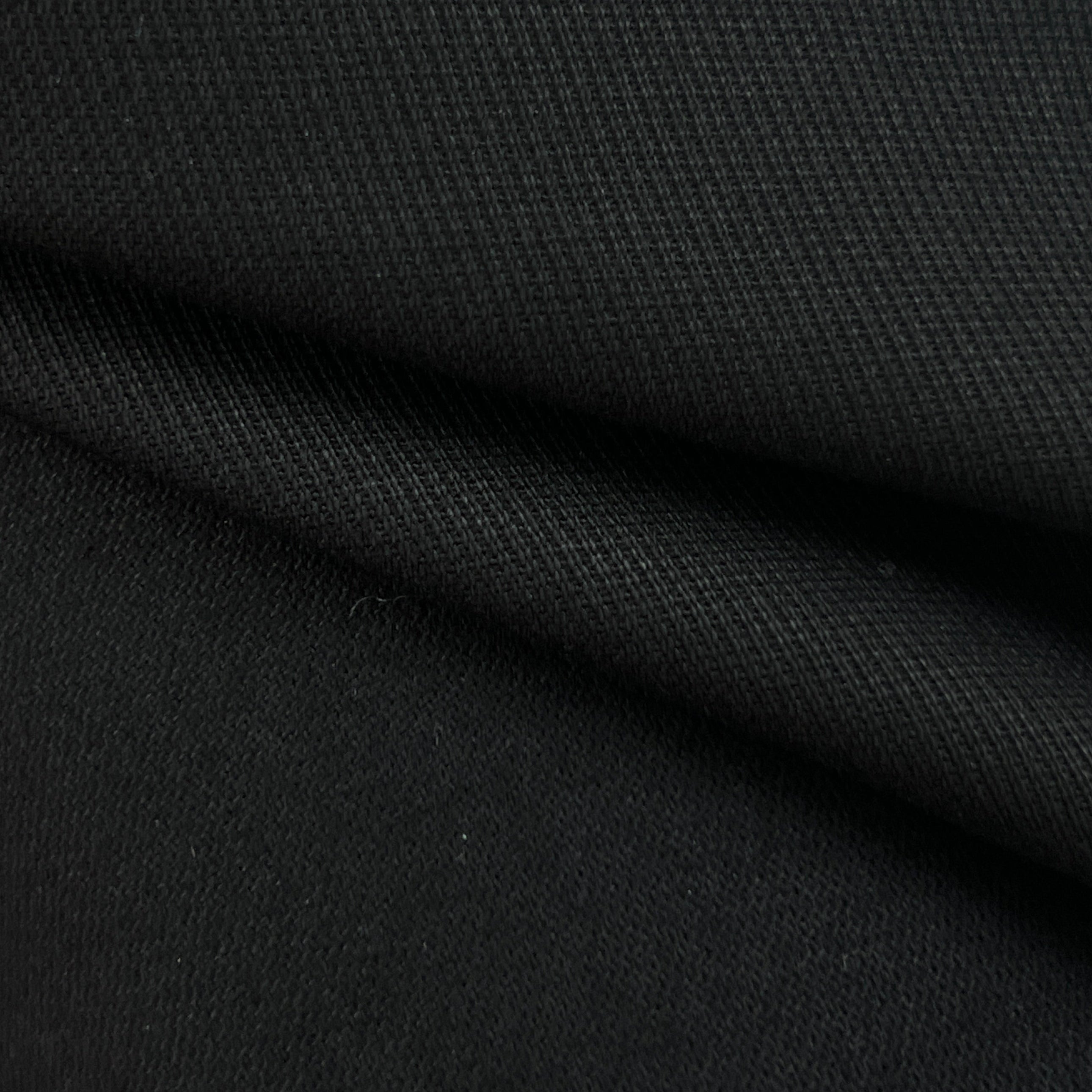 A close-up of black textured fabric with a fine ribbed or woven surface and soft folds.