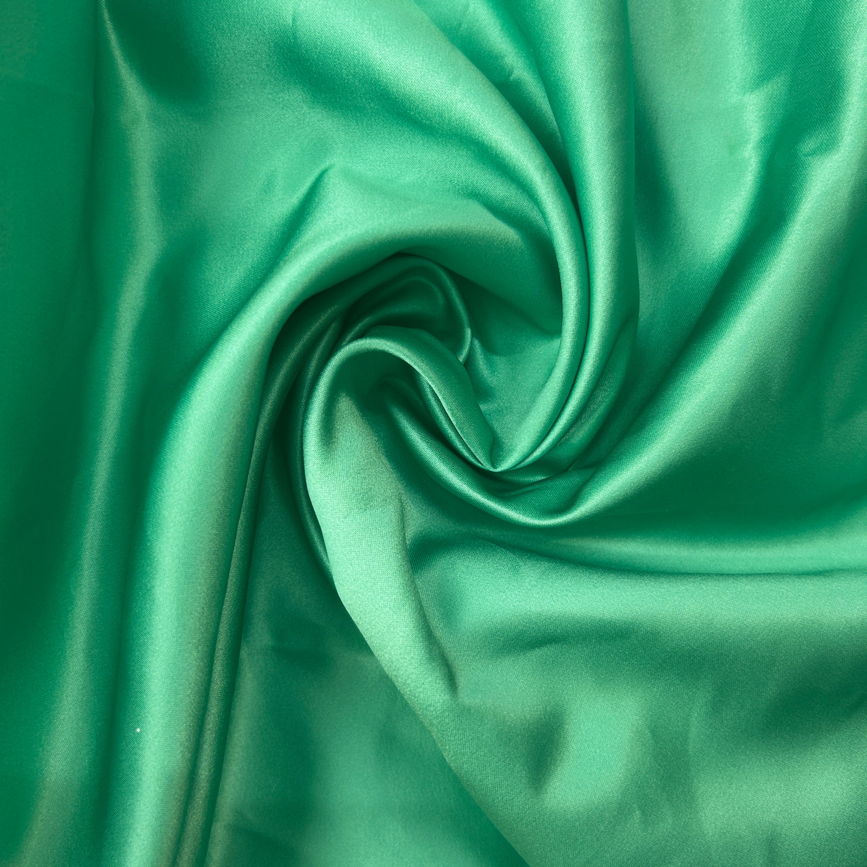 Close-up of green satin fabric with folds