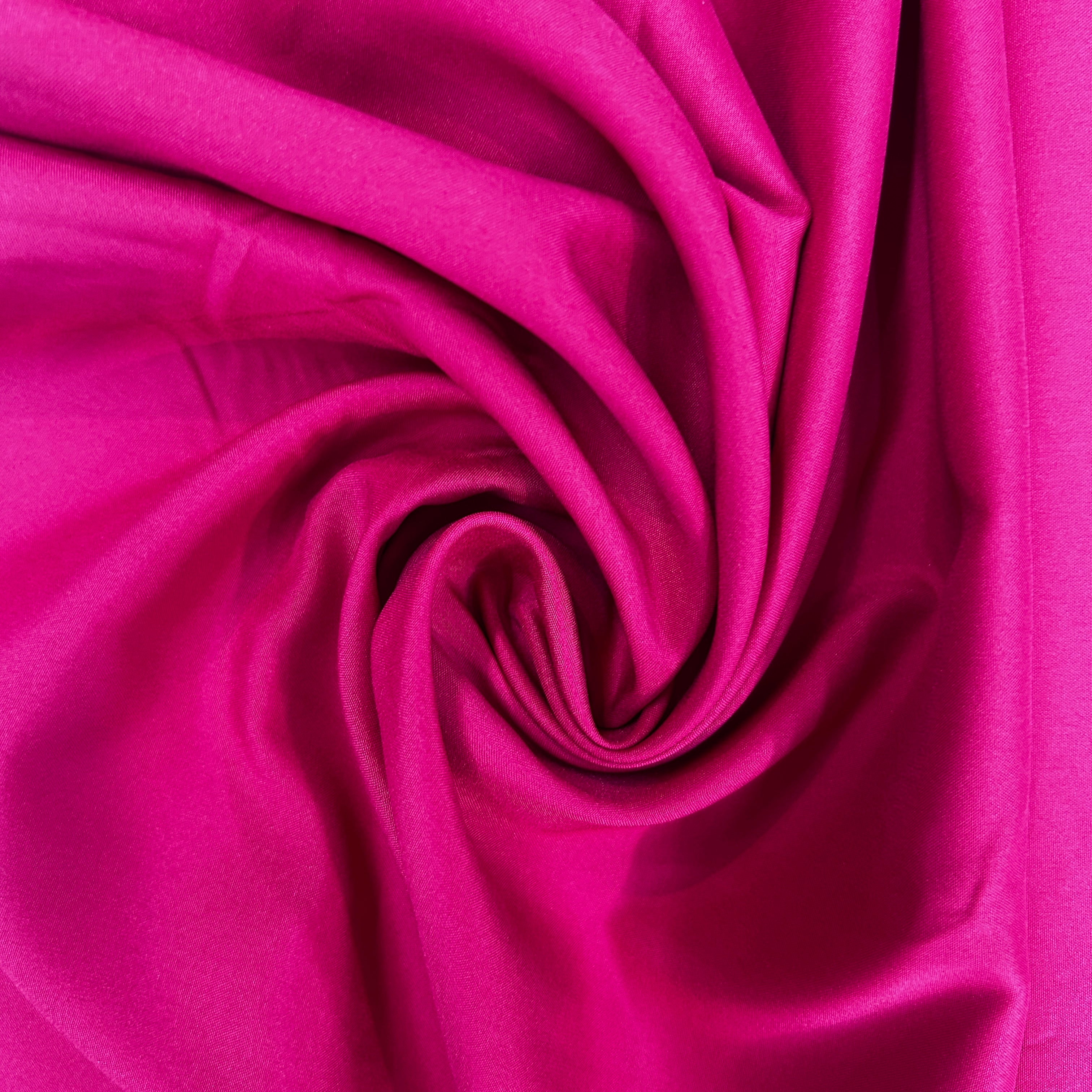Vibrant magenta mechanical stretch polyester fabric swirled into a spiral pattern.