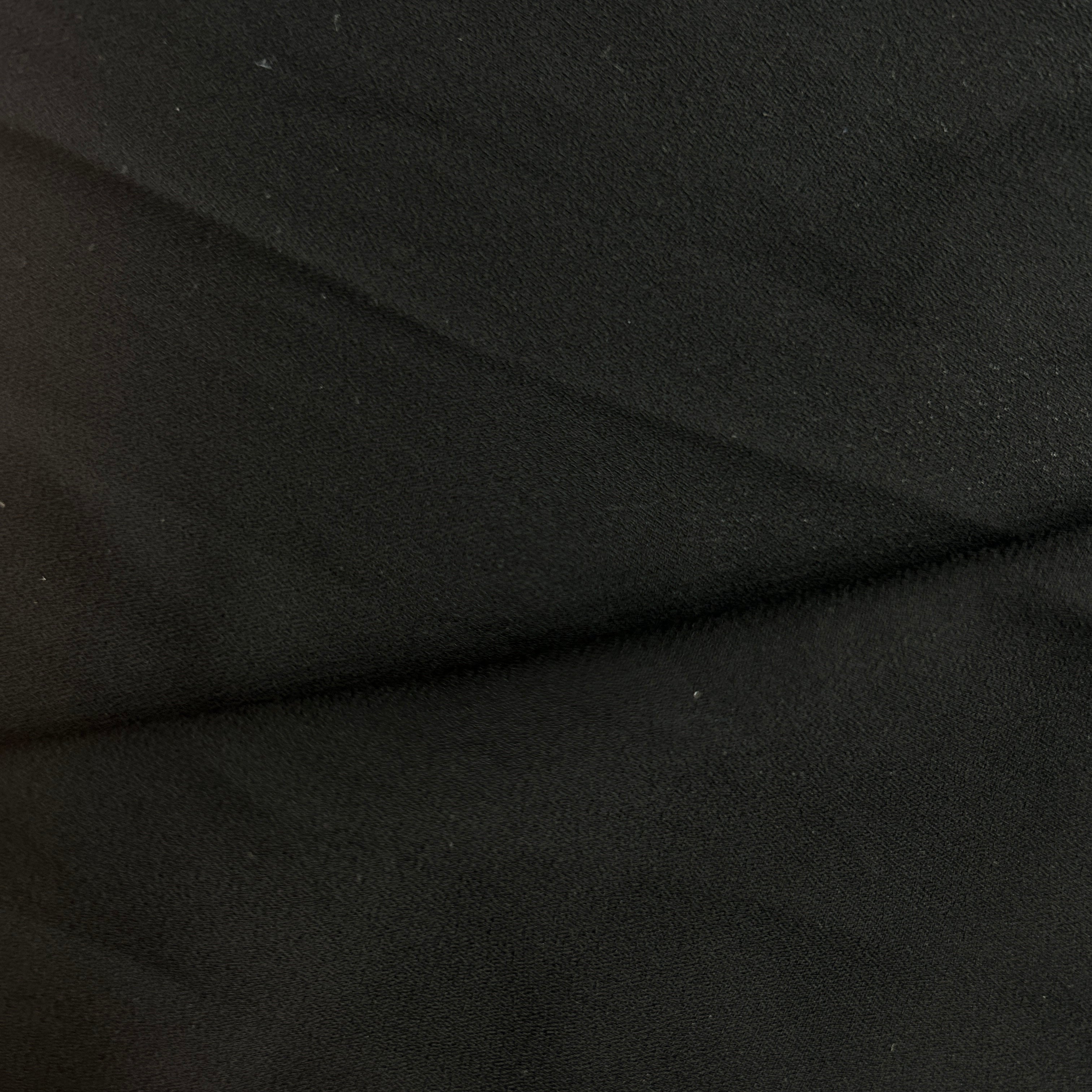 Close-up of black polyester double georgette crepe fabric showing its pebbled matte texture.