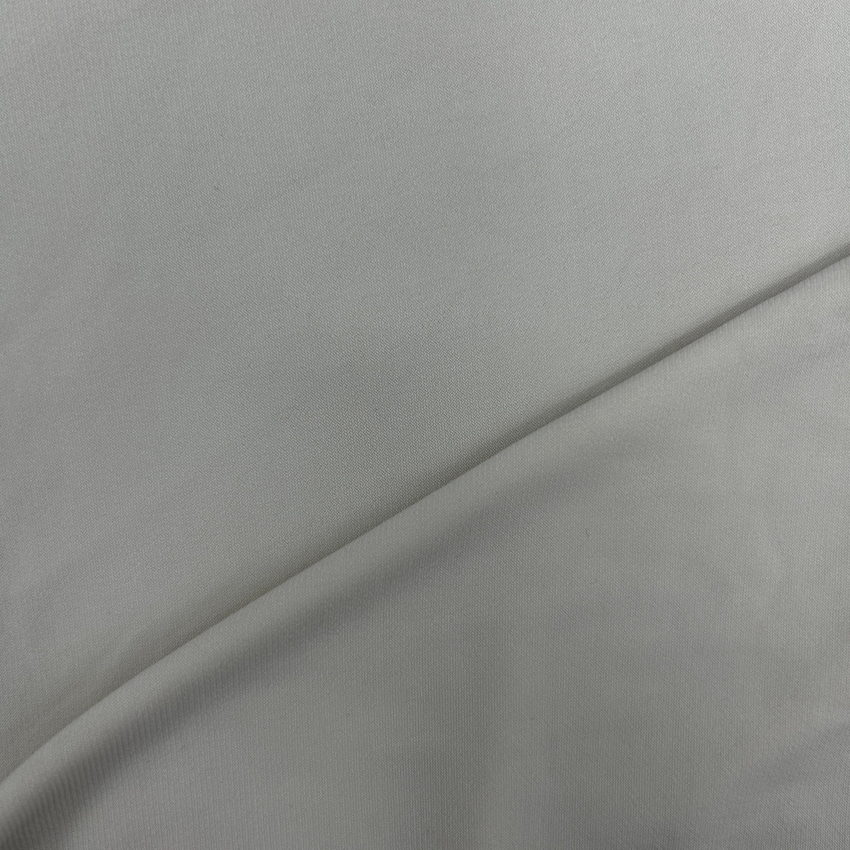A close-up of light gray fabric with a soft diagonal fold.