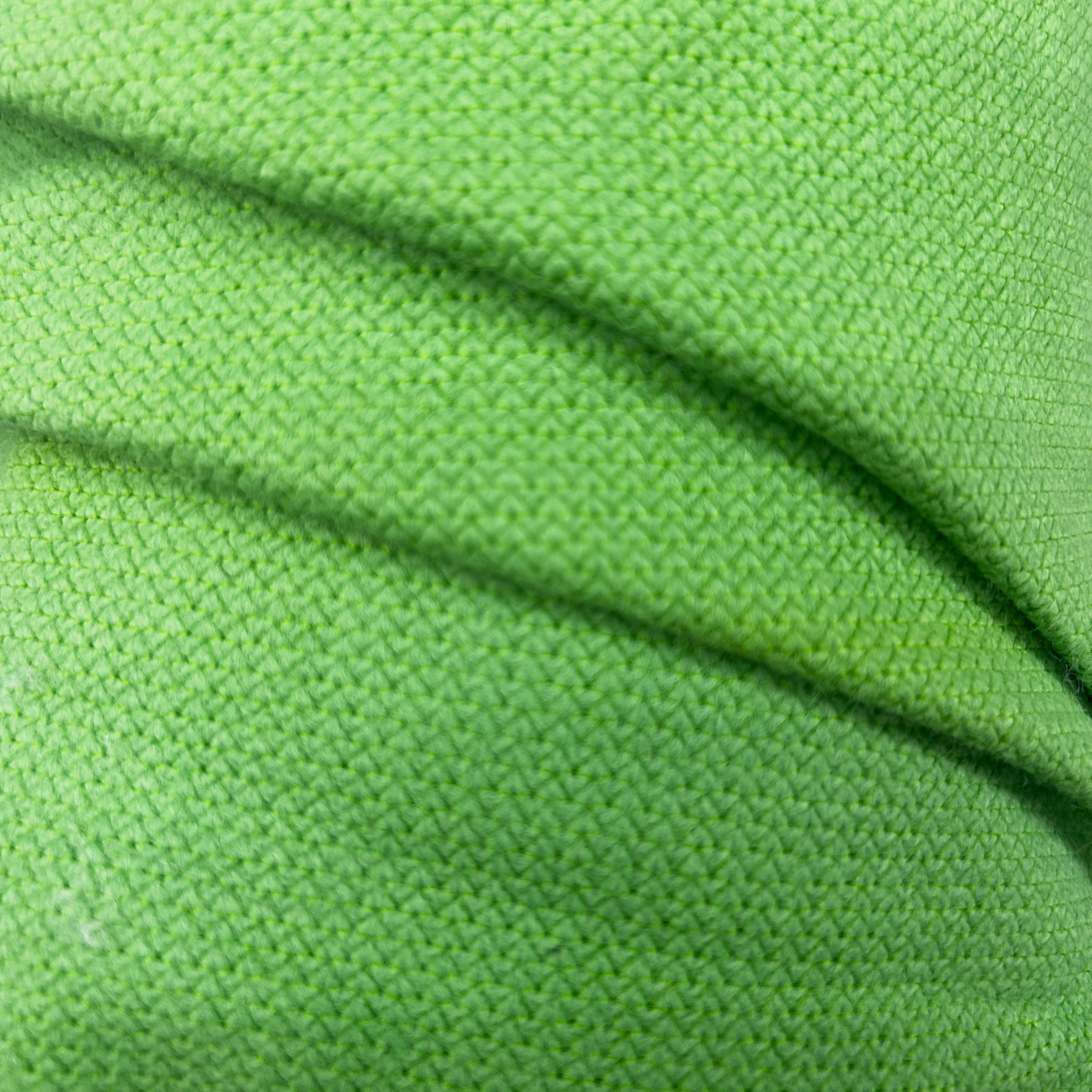 Close-up of vibrant green thick interfacing knit apparel fabric with a textured weave pattern.