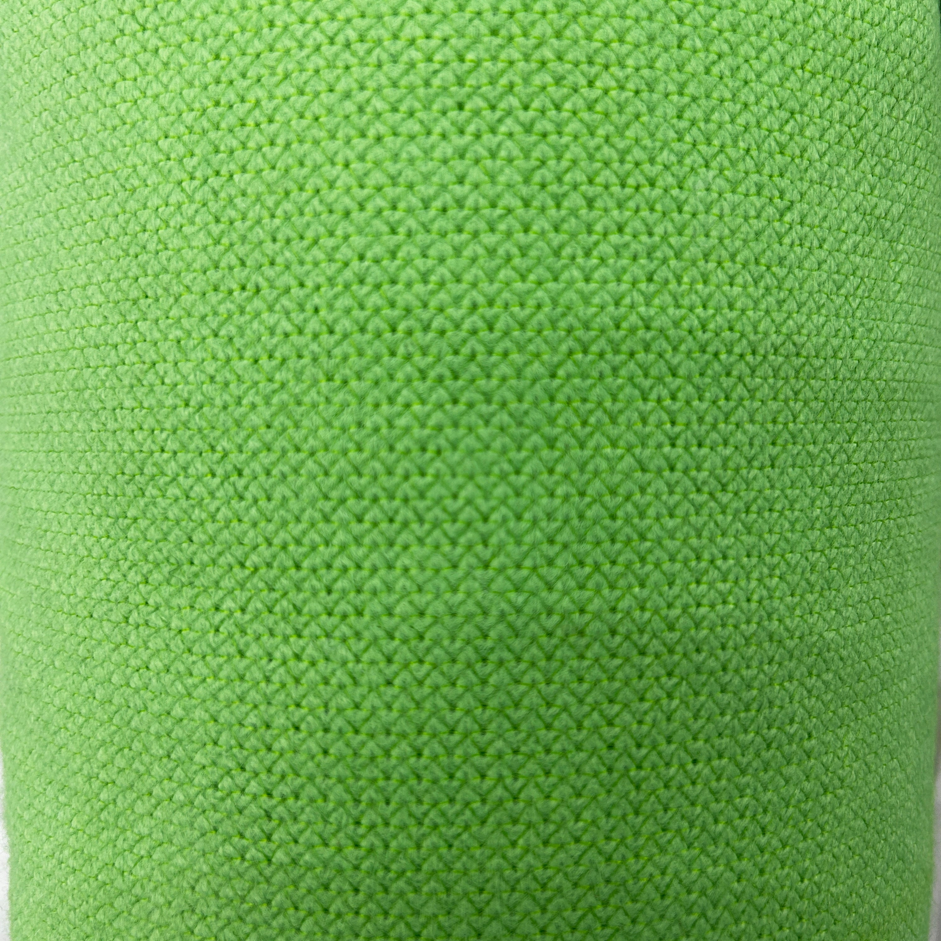 Close-up of green thick interfacing knit apparel fabric with a textured, woven pattern.