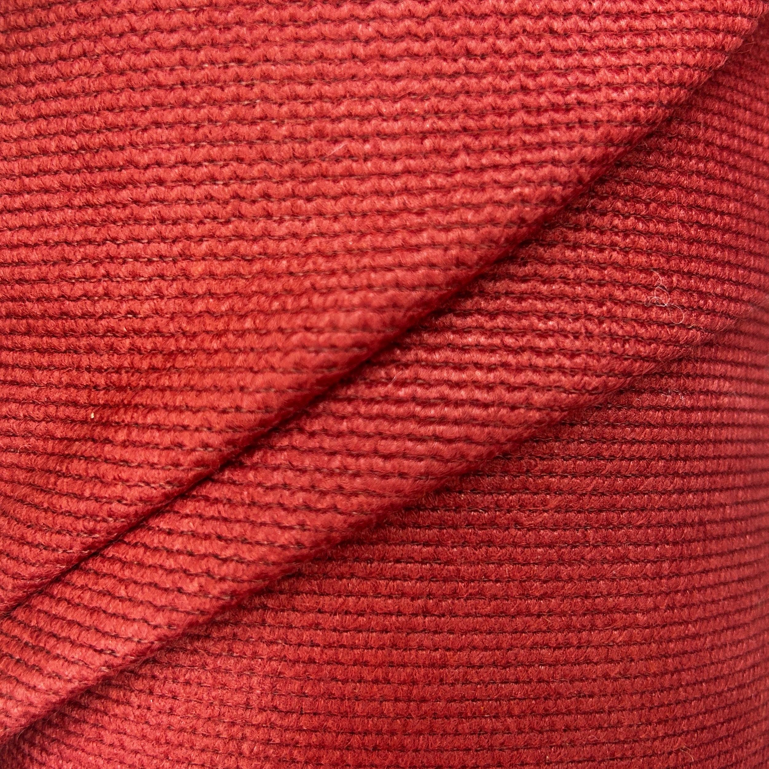 Close-up of red and green thick interfacing knit fabric with a textured, ribbed pattern.