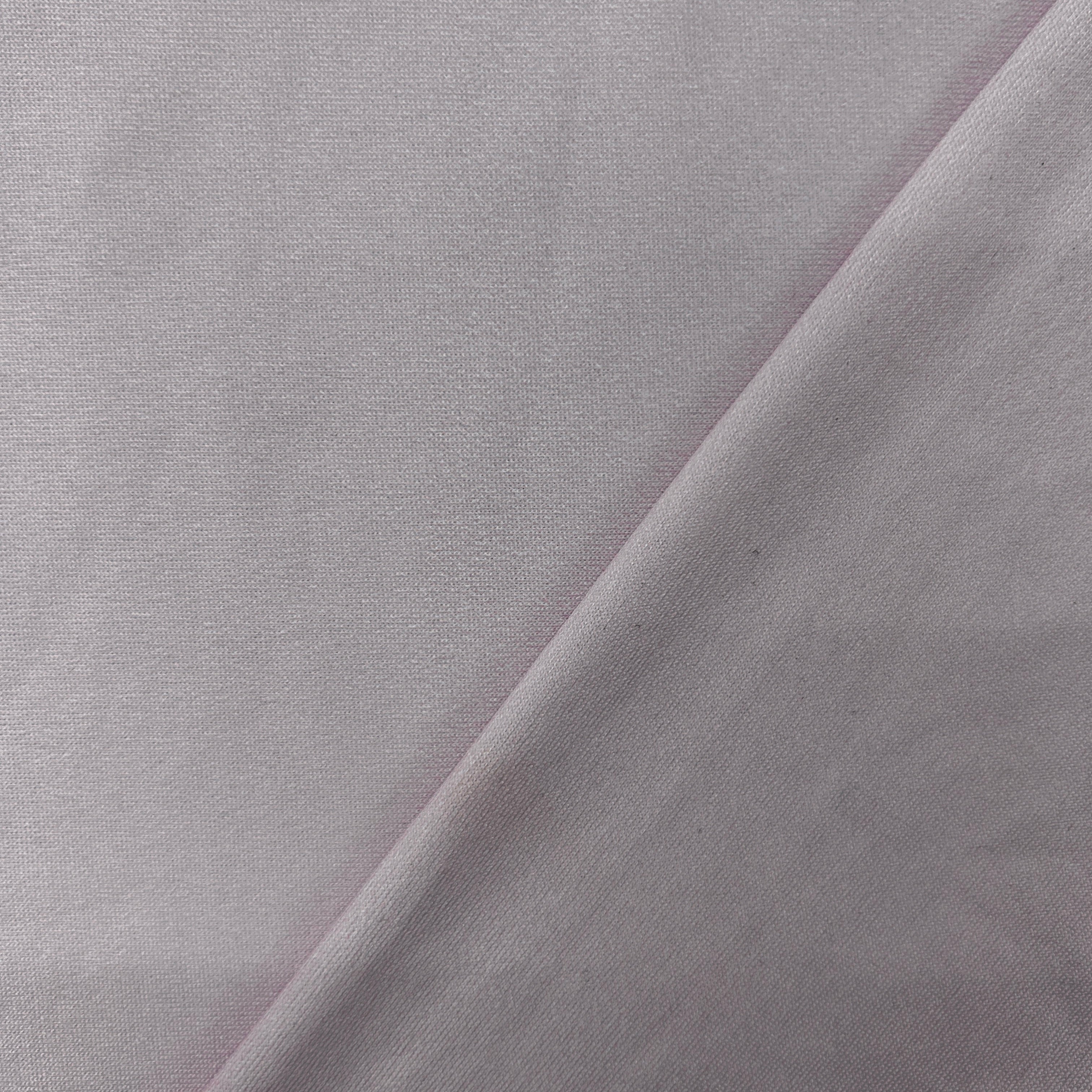 A close-up of light gray fabric with a diagonal fold creating soft shadows.