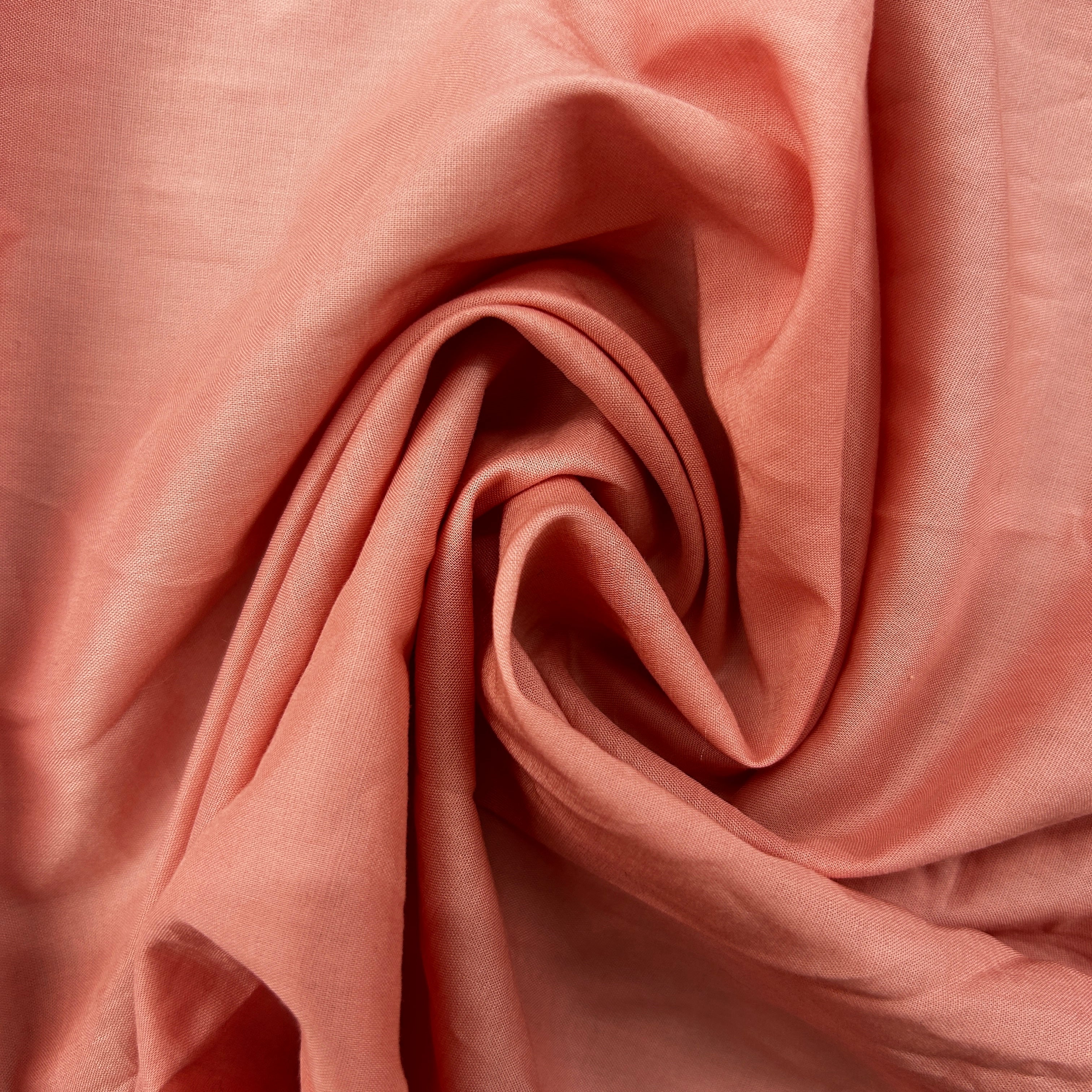 A close-up of draped dusty pink fabric with soft folds and a smooth, slightly lustrous texture.