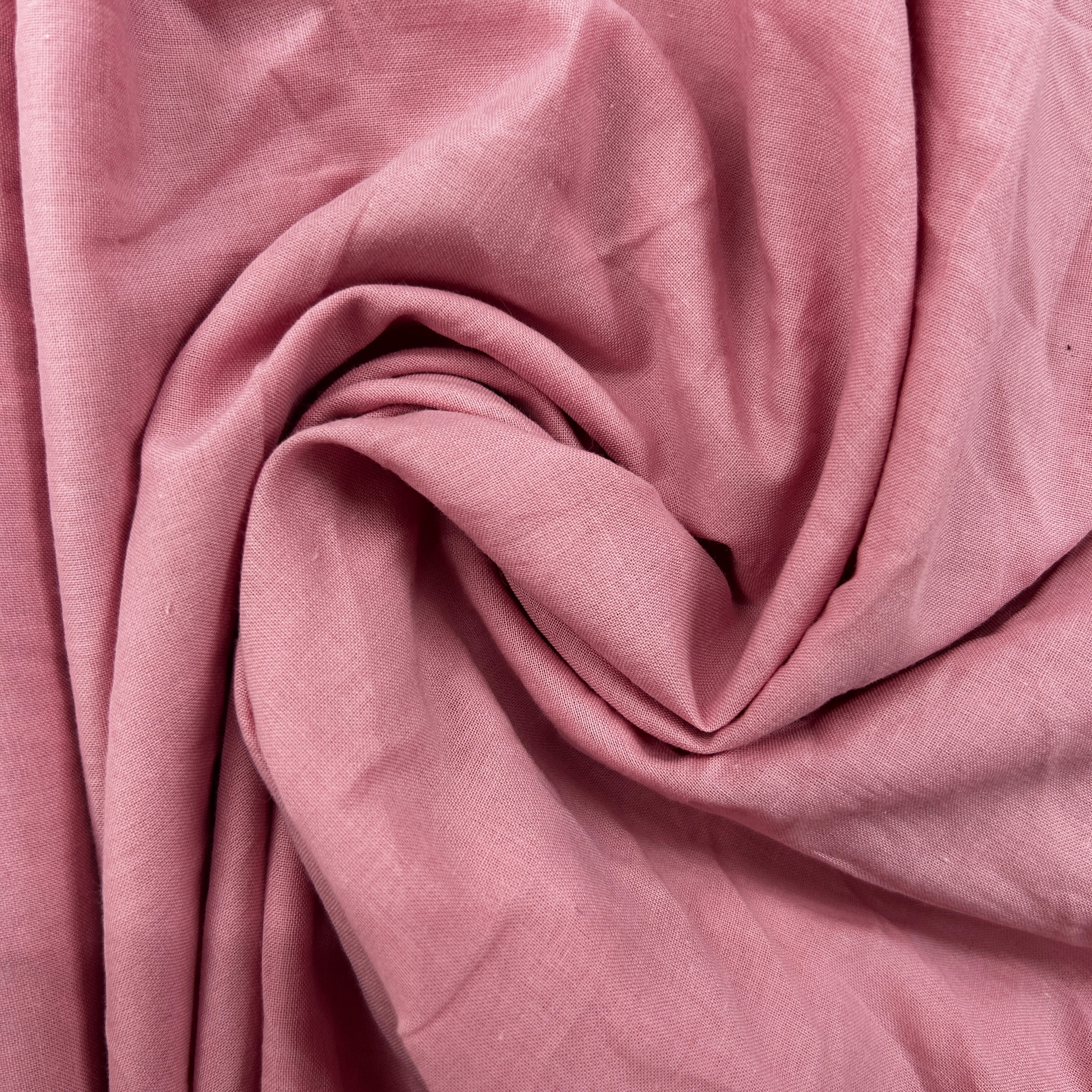 A close-up of draped dusty pink fabric with a soft, textured weave and gentle folds.