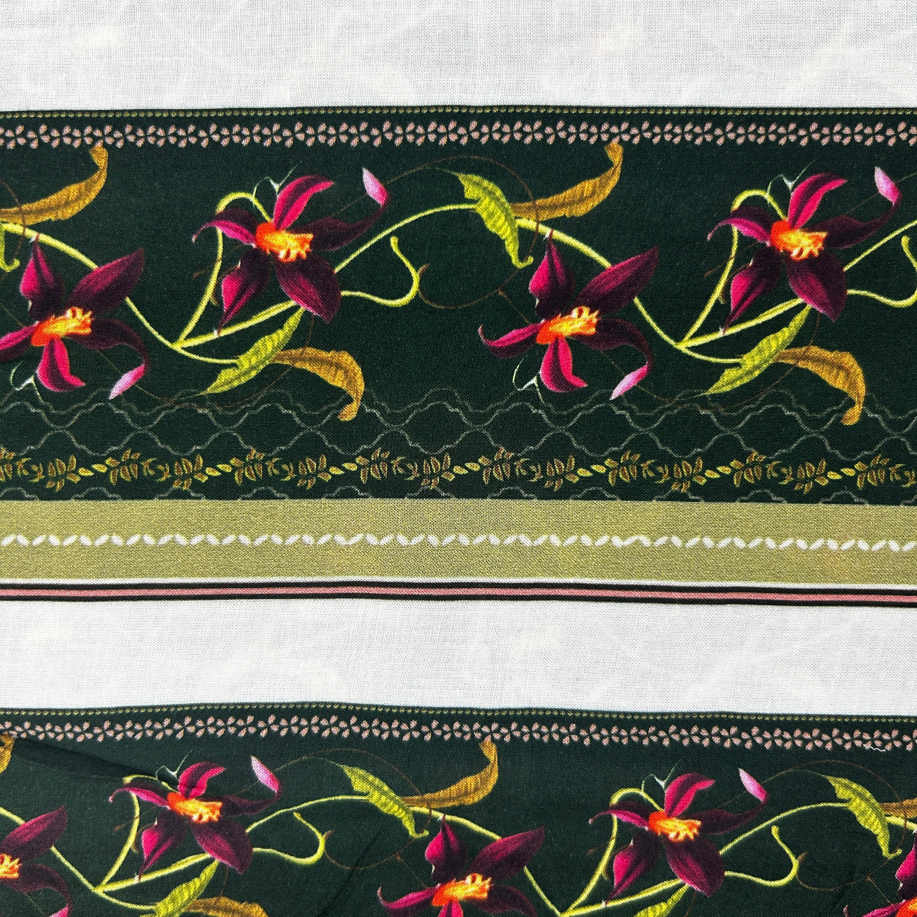 A close-up of a patterned fabric or trim showing dark green bands with burgundy orchids, yellow-green leaves, and gold decorative borders on a white background.
