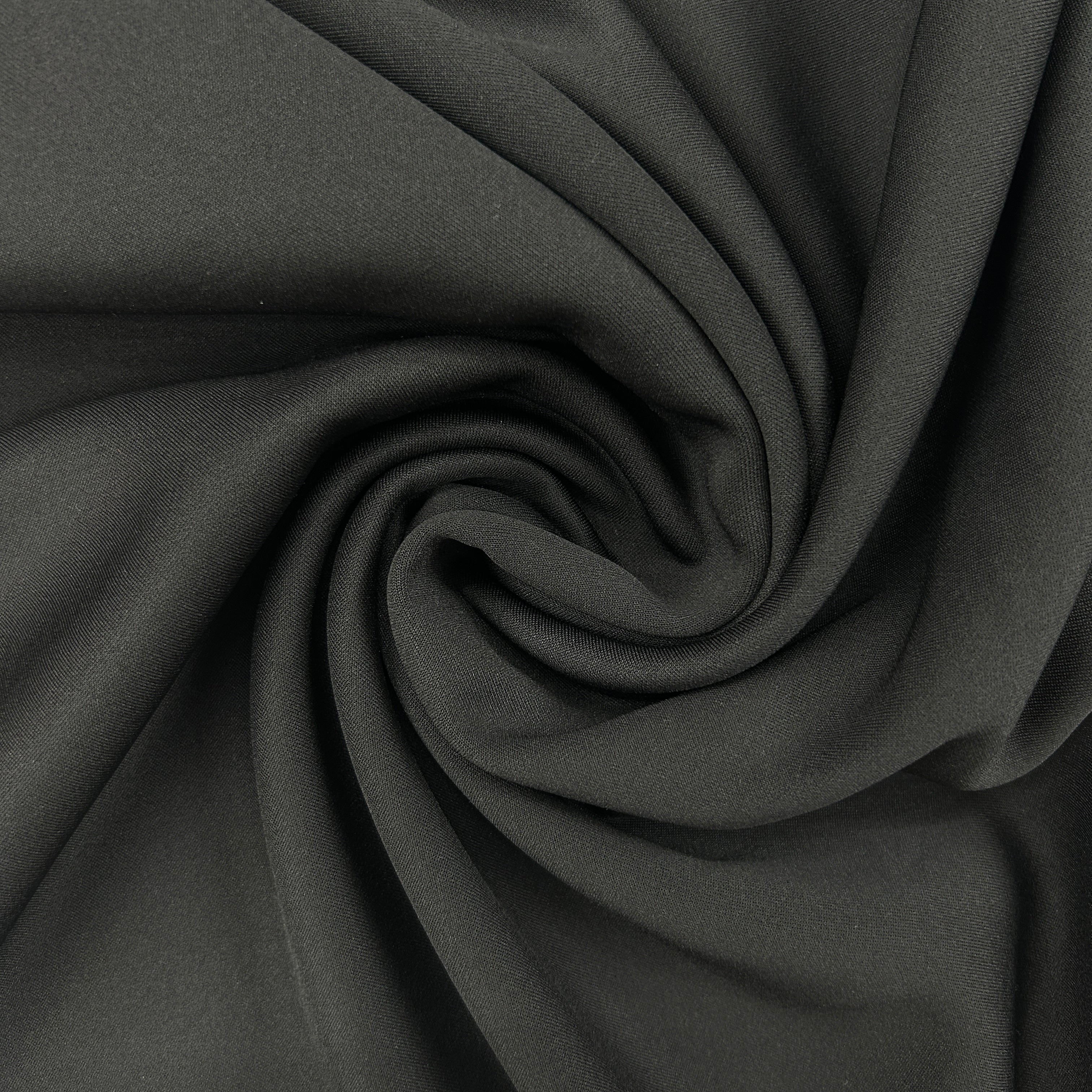 A close-up of dark charcoal gray fabric arranged in a spiral drape, showing its smooth texture and soft folds.