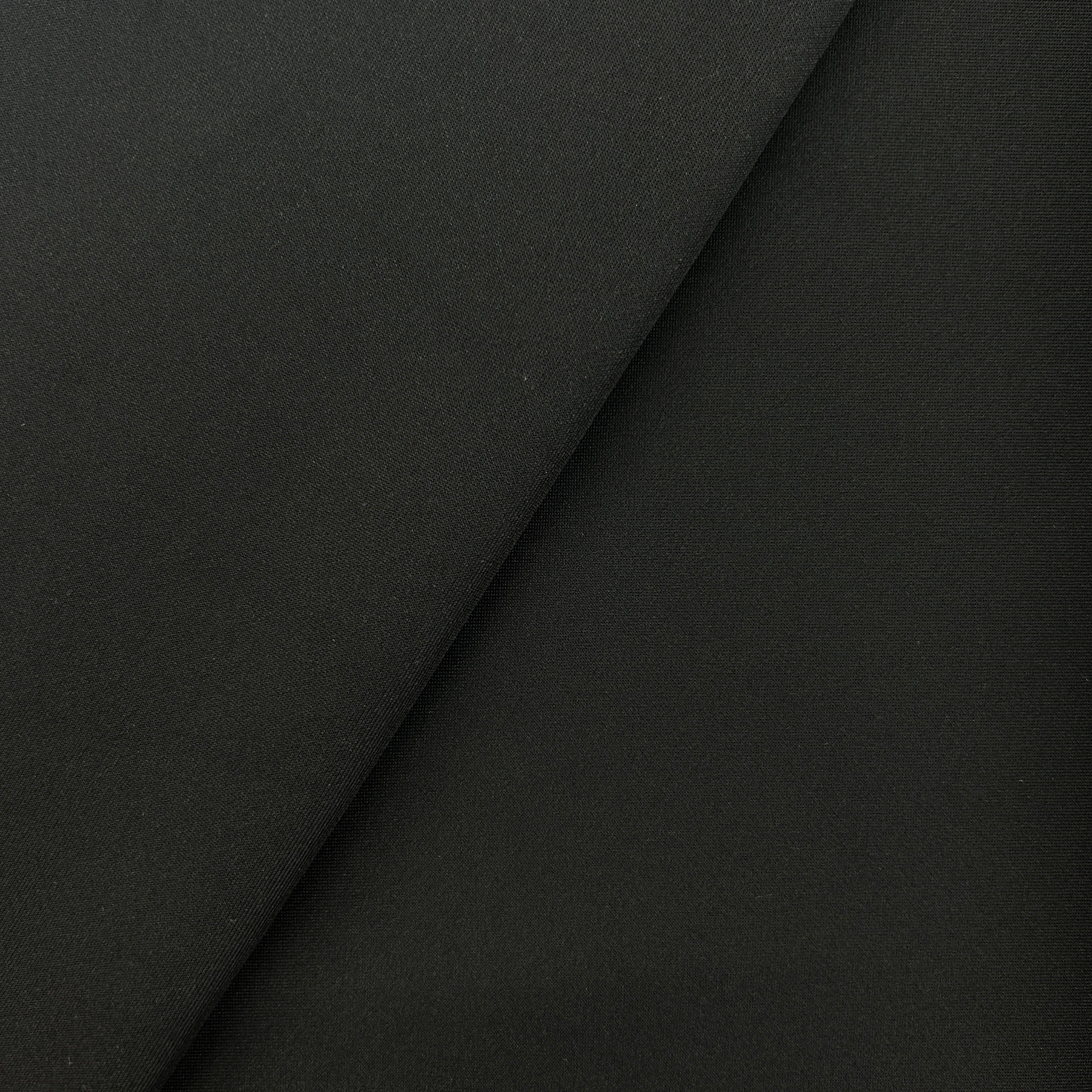 A close-up of a solid black fabric with a soft diagonal fold.