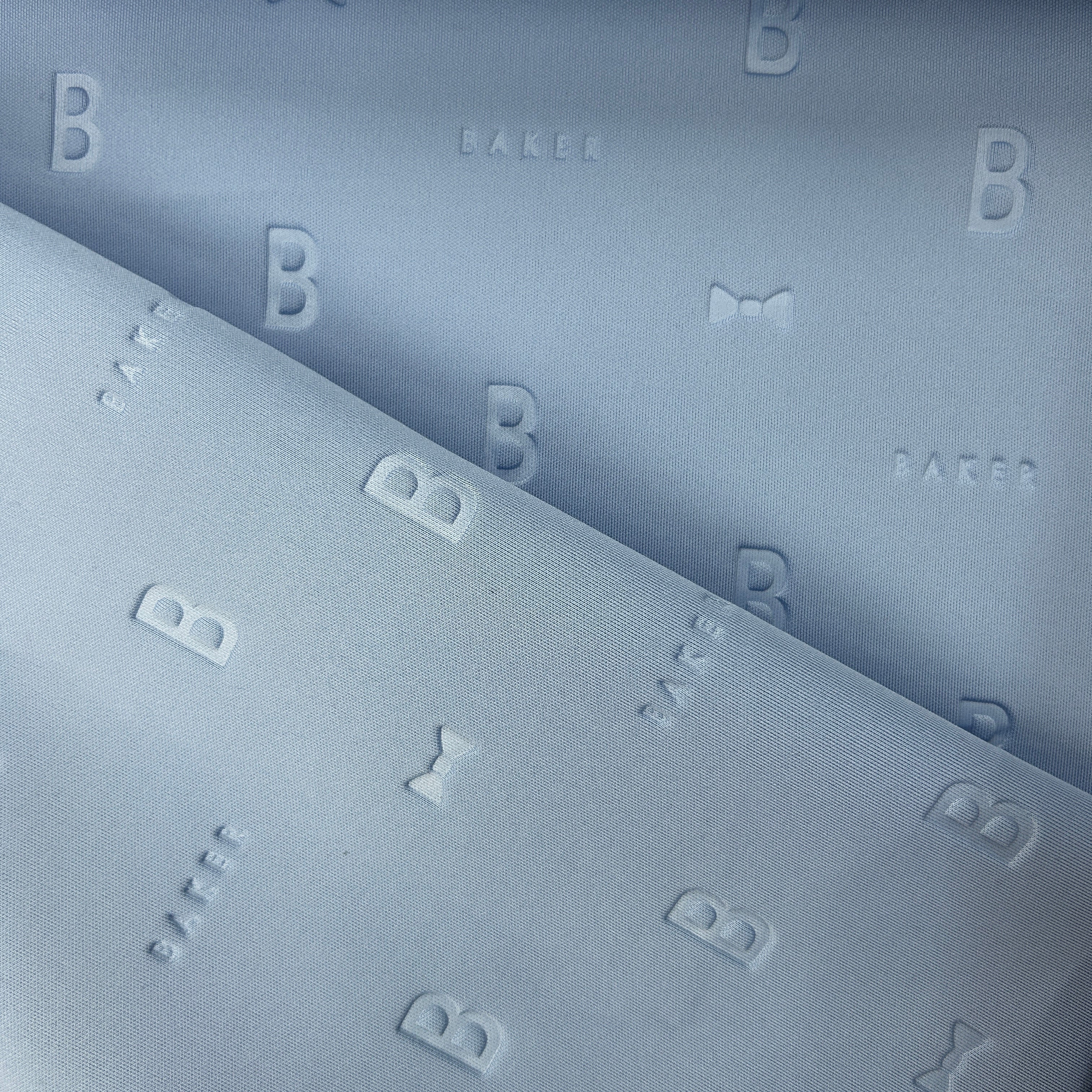 Close-up of periwinkle blue 3D Ted Baker scuba jersey fabric with embossed B and bow tie patterns.