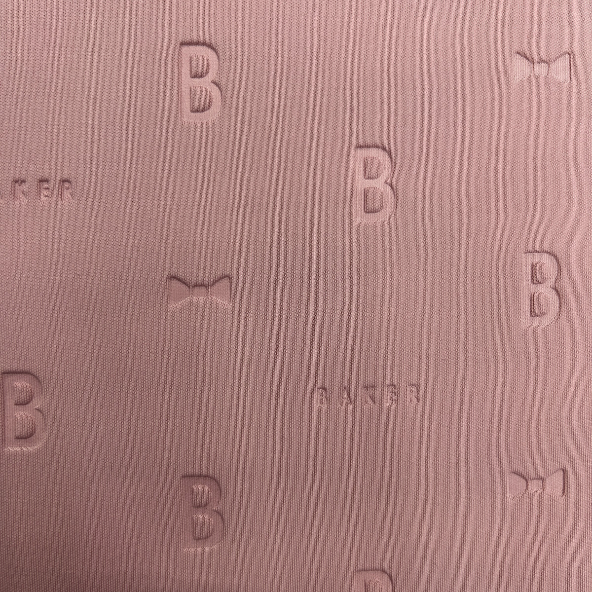 Close-up of mauve 3D Ted Baker thick scuba jersey fabric with embossed 'B' and bow patterns.