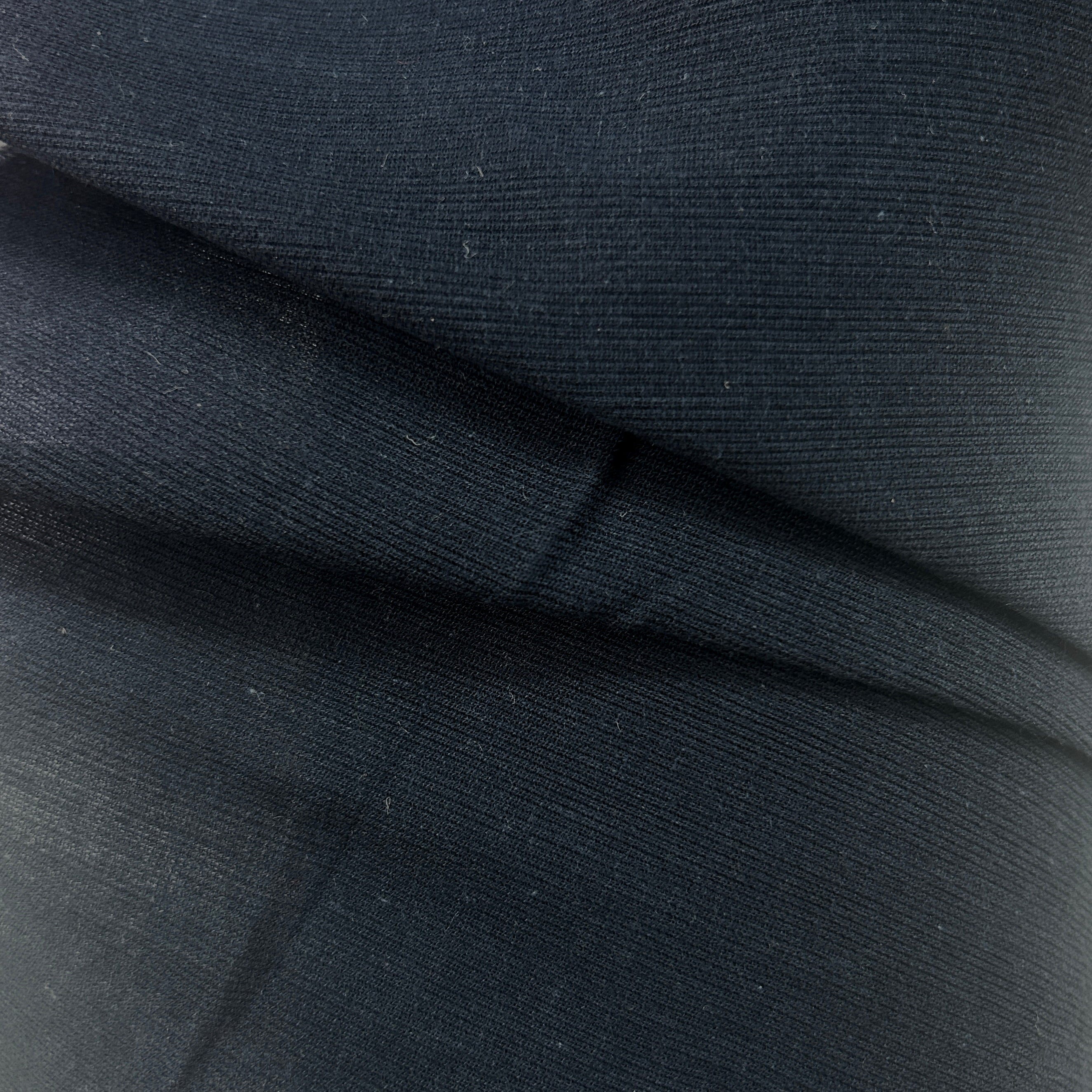 A close-up of dark charcoal gray ribbed fabric with a fine textured weave, showing soft folds and creases.