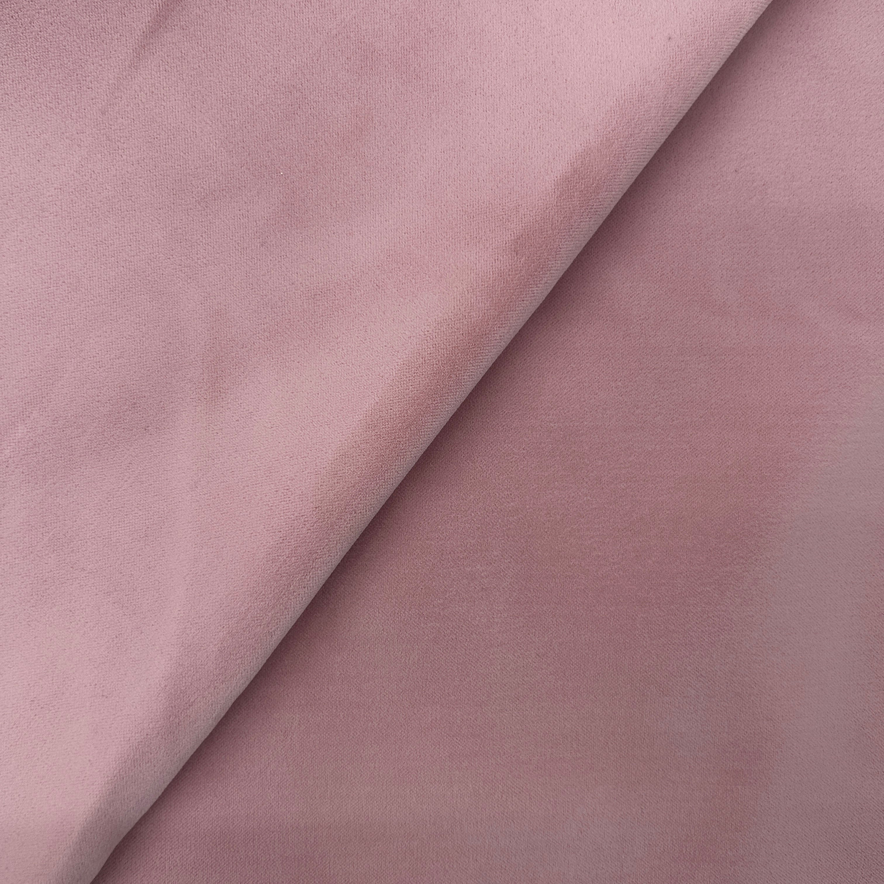 A close-up of dusty pink fabric with a soft, matte texture, folded diagonally across the frame.
