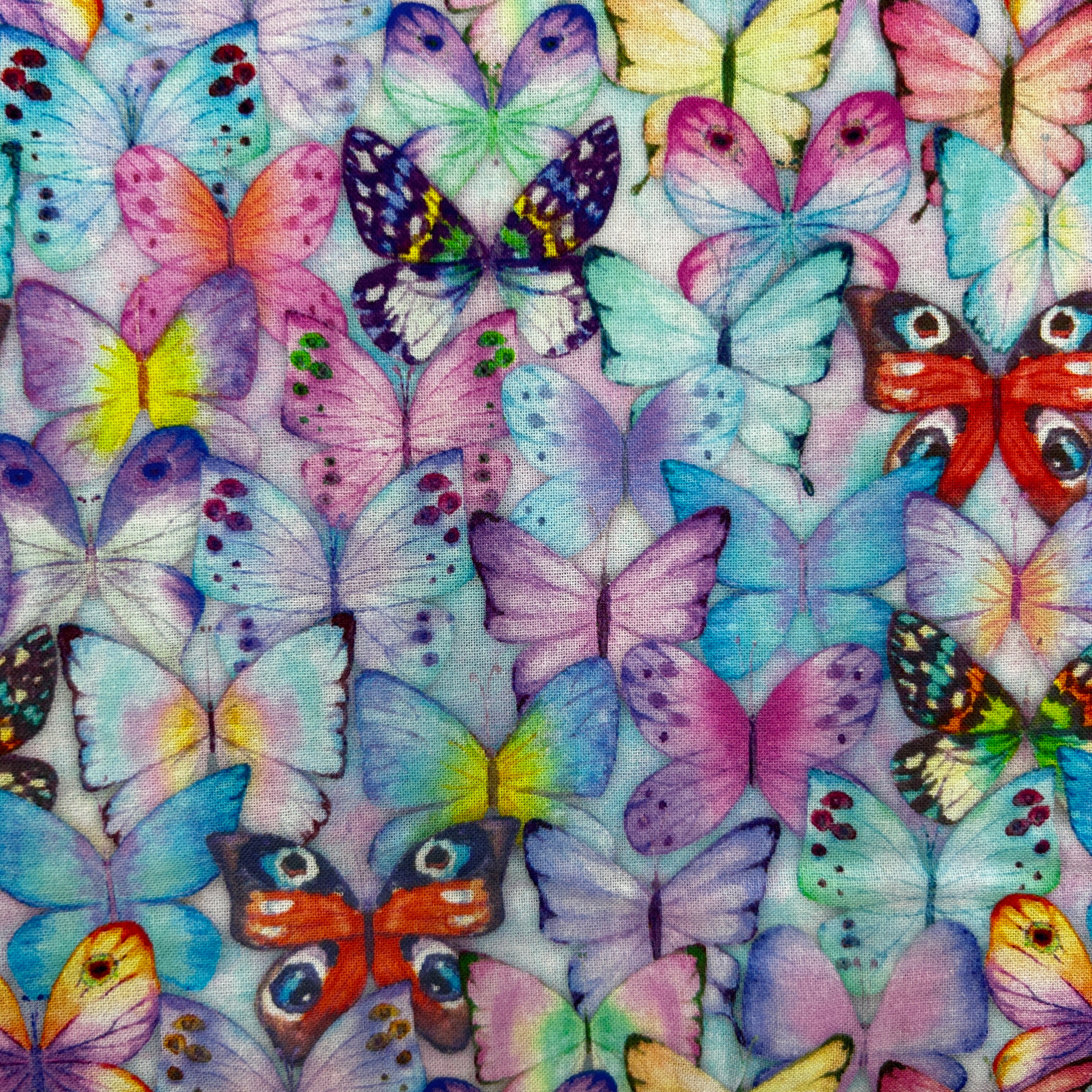 A close-up of a fabric or wallpaper pattern featuring a dense, colorful print of watercolor-style butterflies in shades of purple, blue, pink, yellow, orange, and green on a pale lavender background.