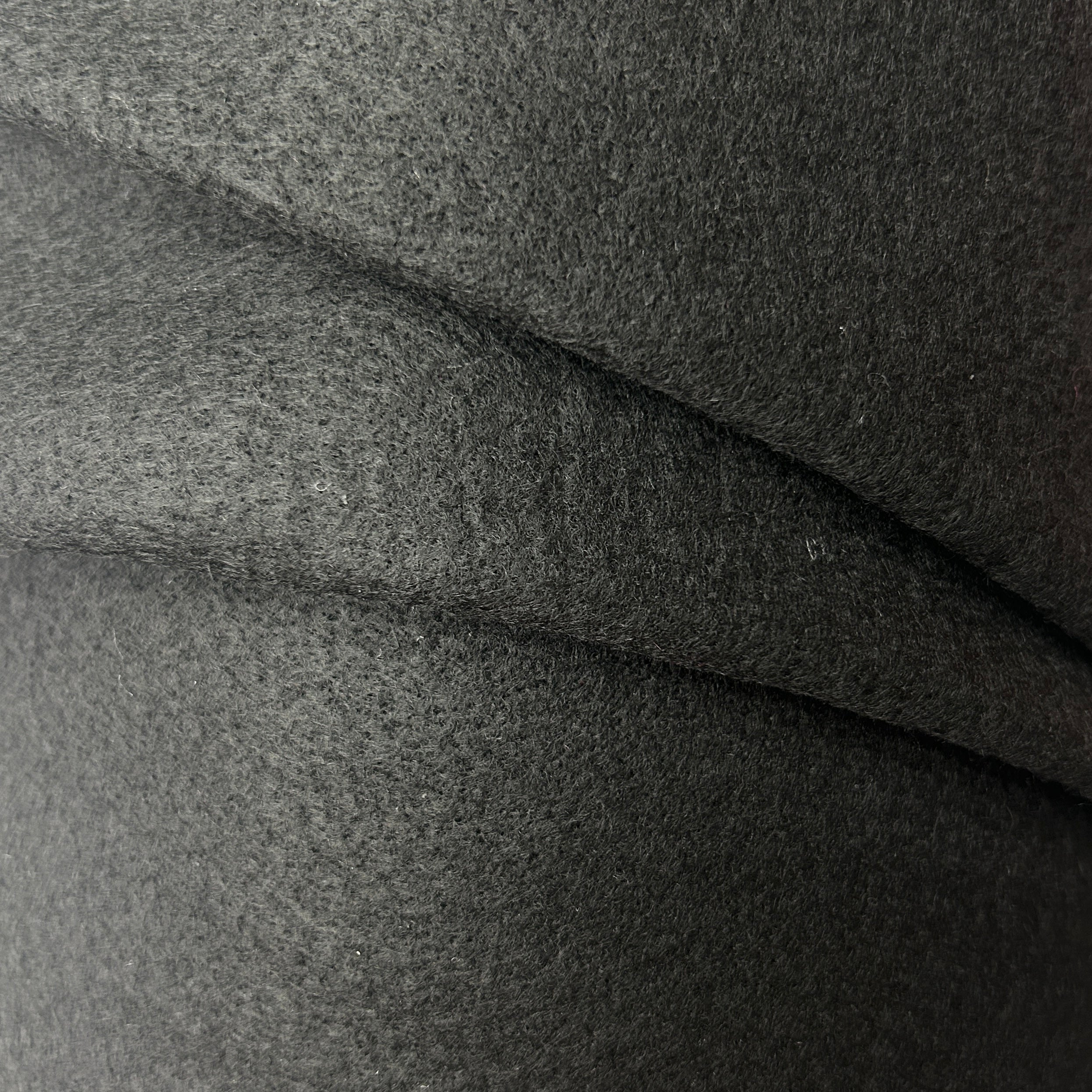 A close-up of dark charcoal gray felt fabric with soft folds showing its textured, fibrous surface.