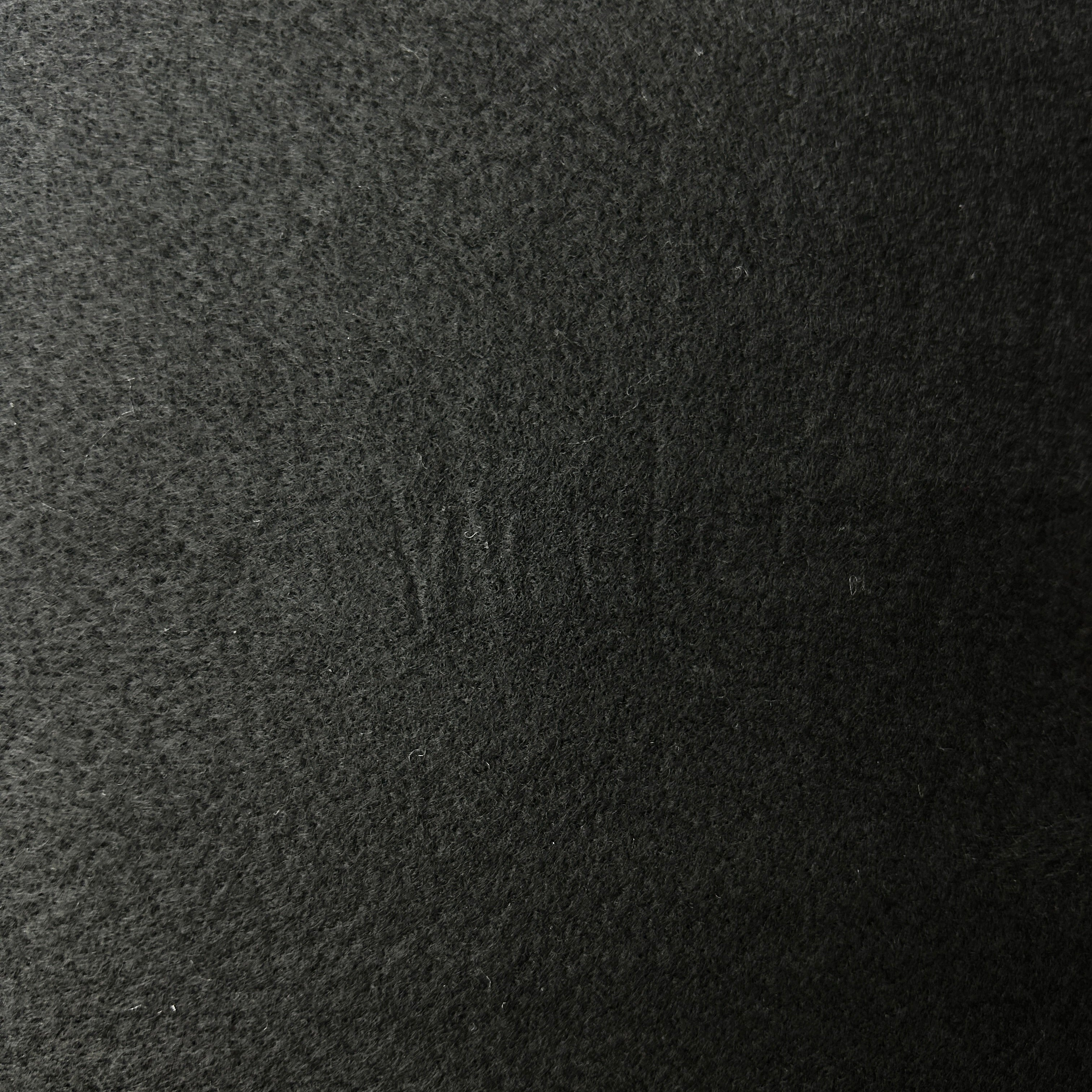A close-up texture shot of a dark charcoal gray felt or wool fabric, filling the entire frame.