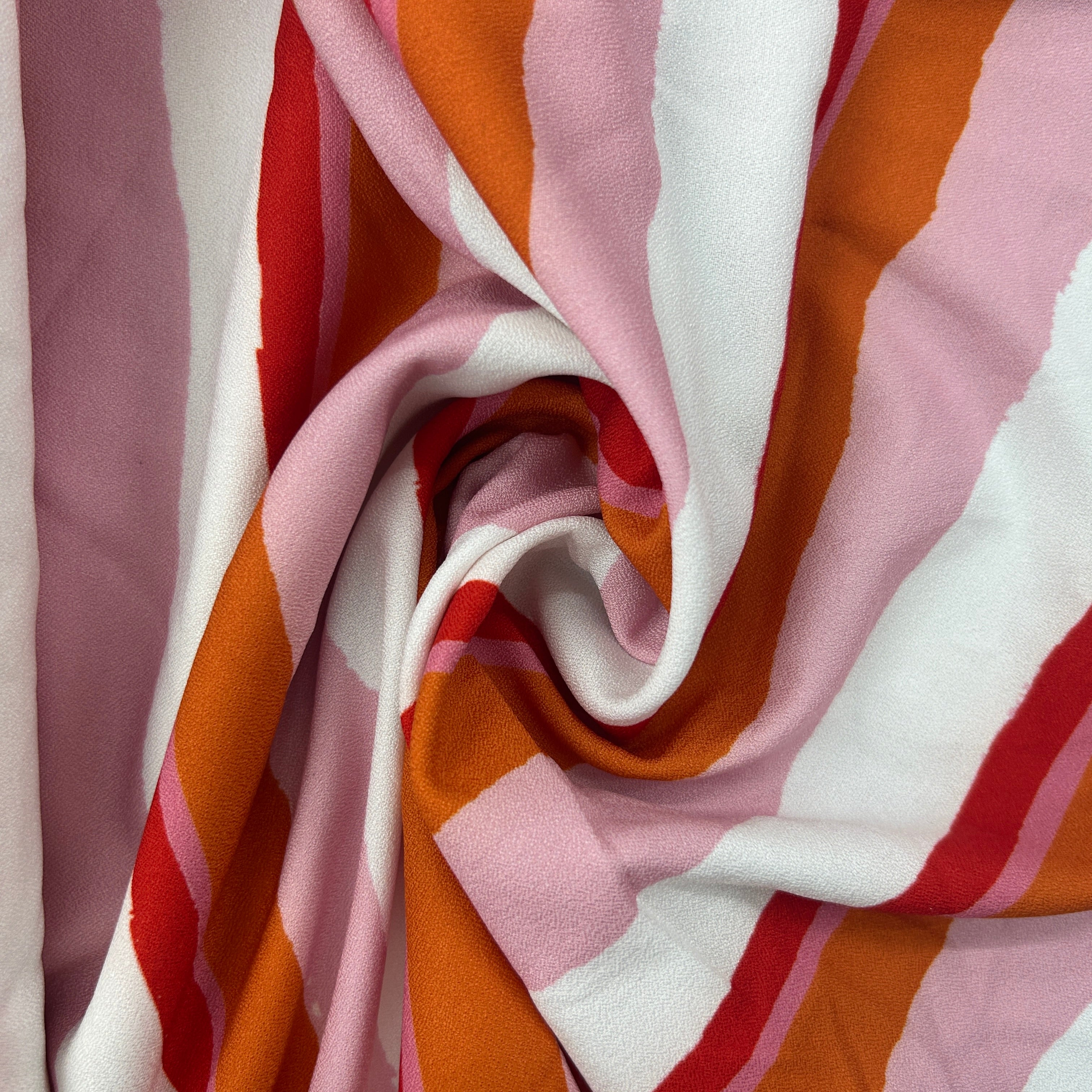 A close-up of draped striped fabric with alternating wide bands of white, dusty pink, burnt orange, and red.