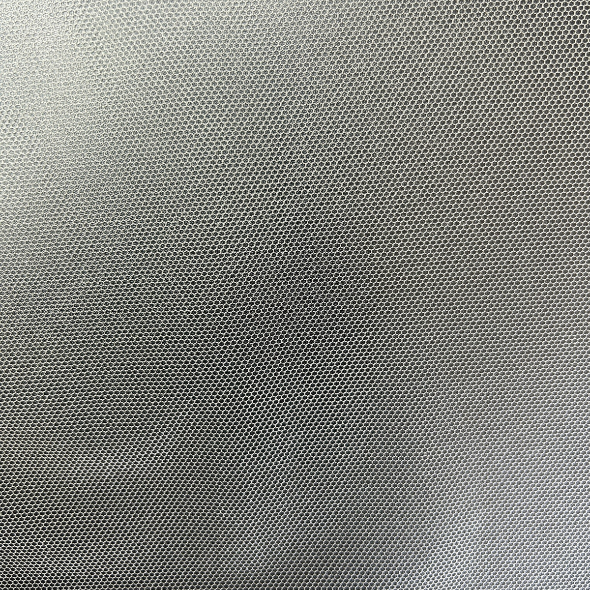 Close-up of black lightweight polyester tulle mesh fabric with a fine hexagonal grid pattern.