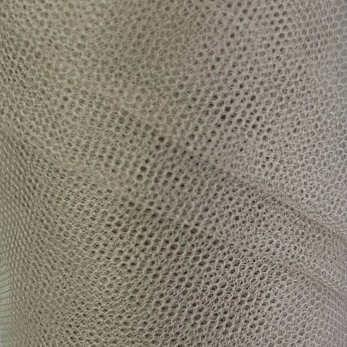 A close-up of a light gray or off-white mesh fabric with a fine, repeating perforated pattern and soft folds.