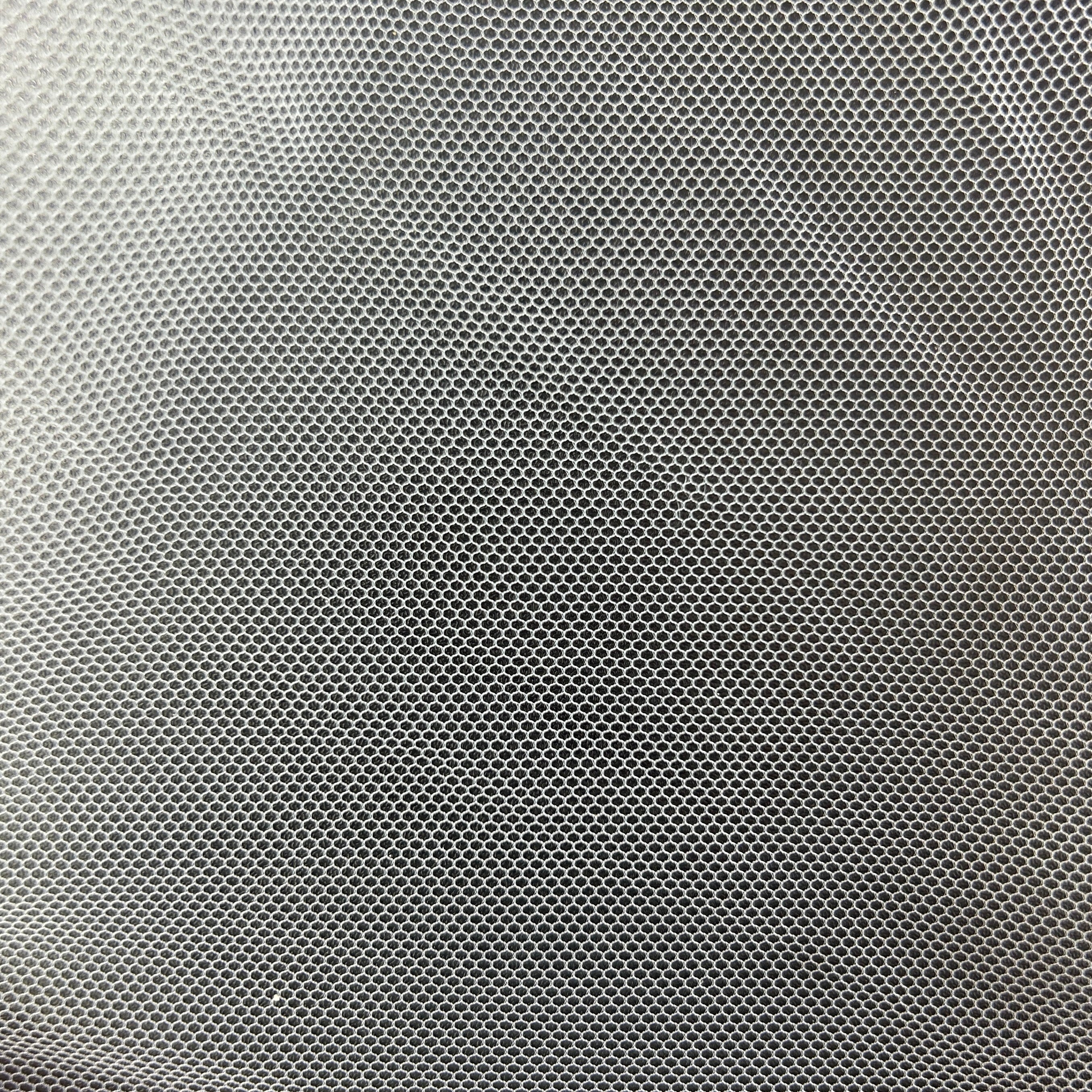 Close-up of white polyester tulle mesh fabric with a fine, open hexagonal grid pattern.