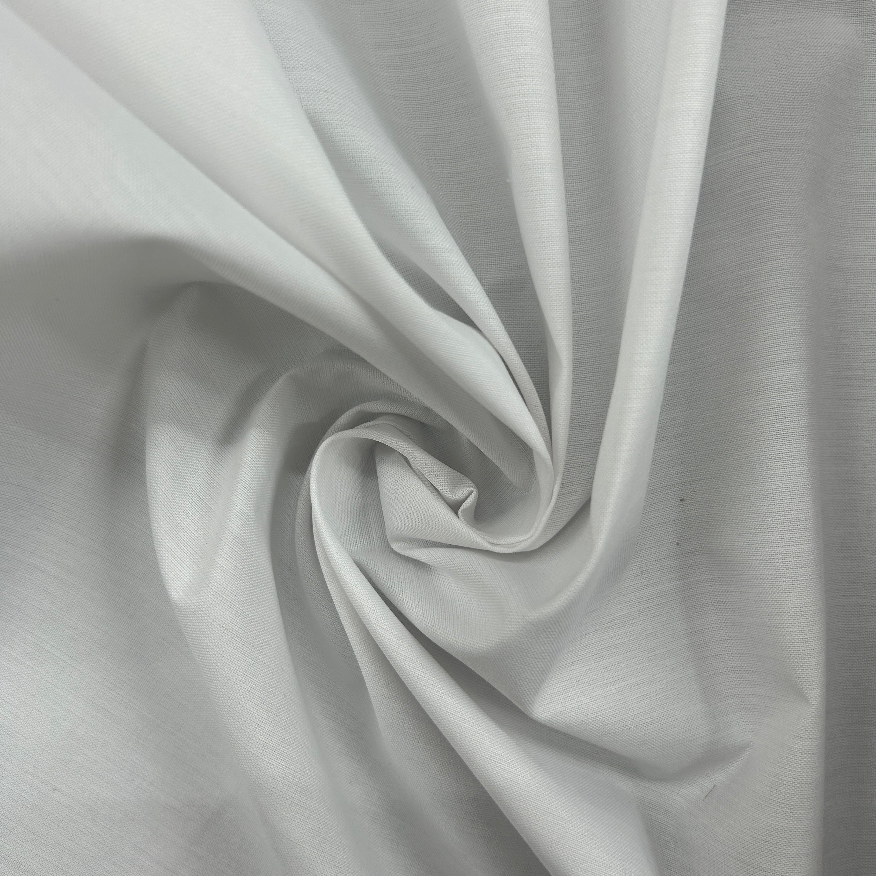 A close-up of light gray fabric arranged in a spiral drape, showing the material texture and soft folds.