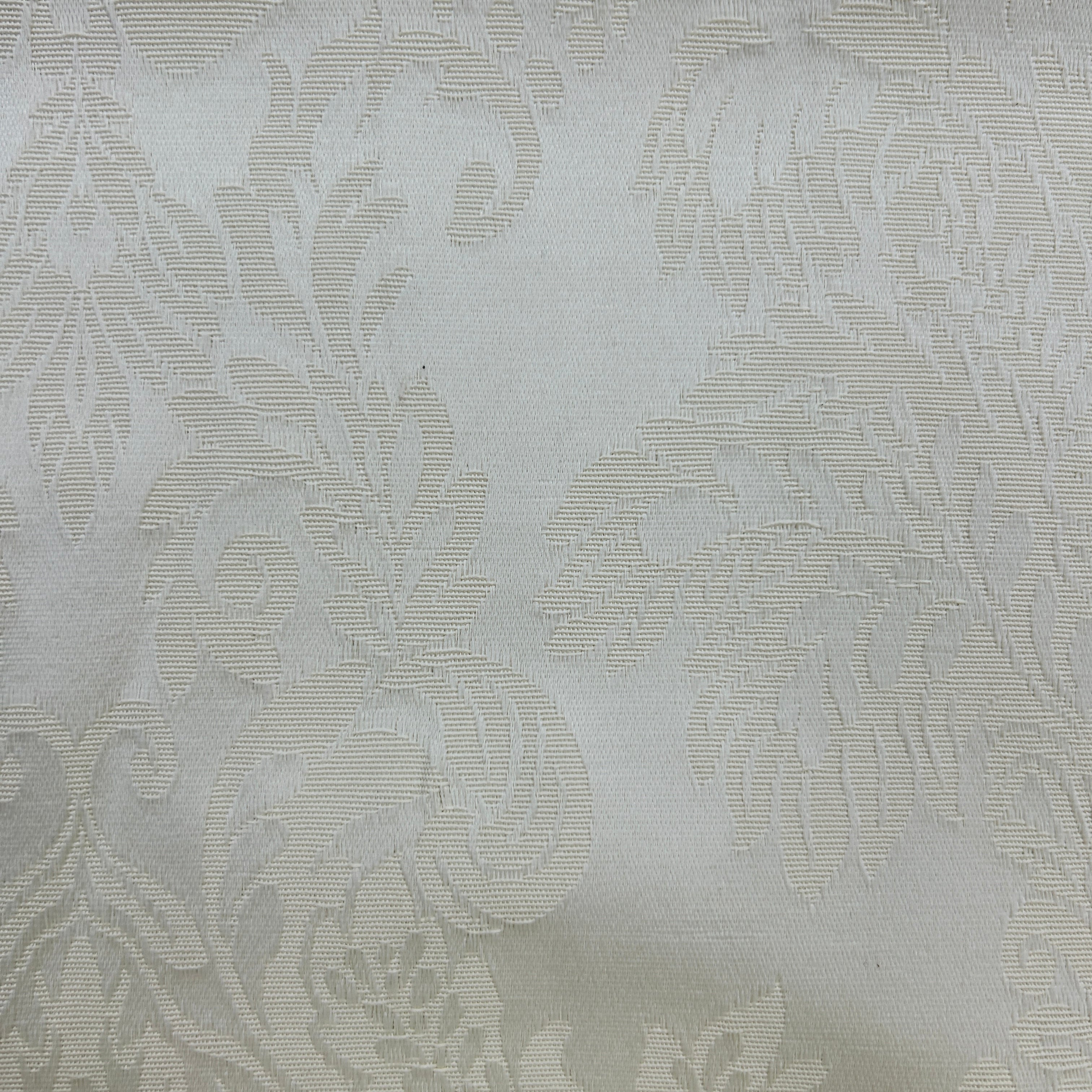 A close-up of a light beige or off-white fabric with a subtle woven damask floral pattern.