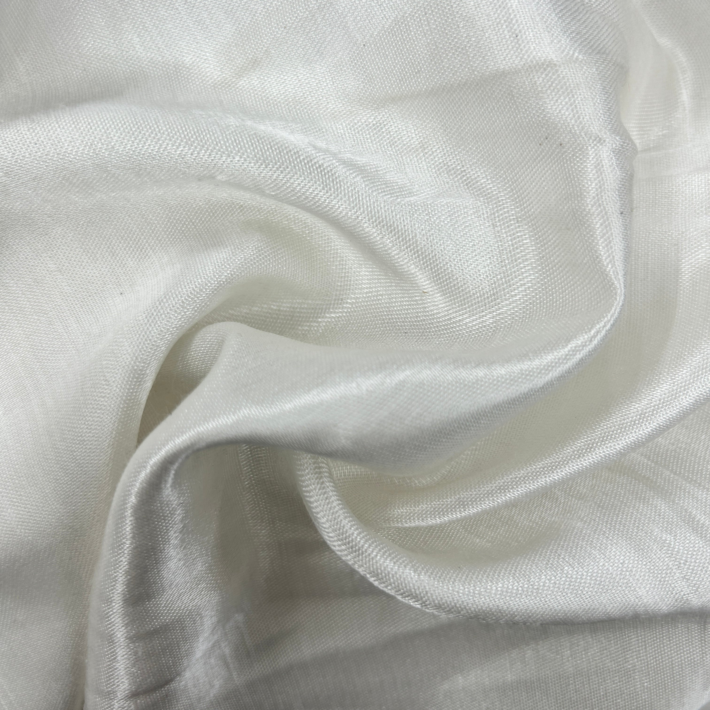 A close-up of draped white fabric with a subtle woven texture and soft folds.