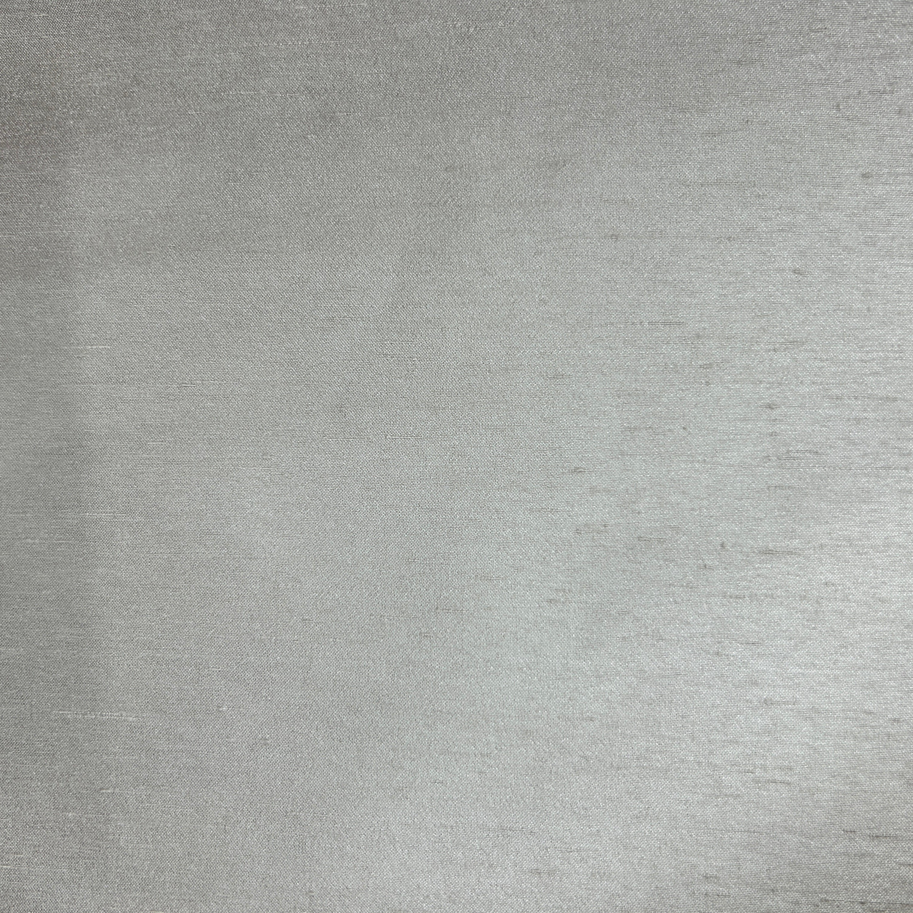 A close-up of a brushed silver metal surface with a fine, textured finish.