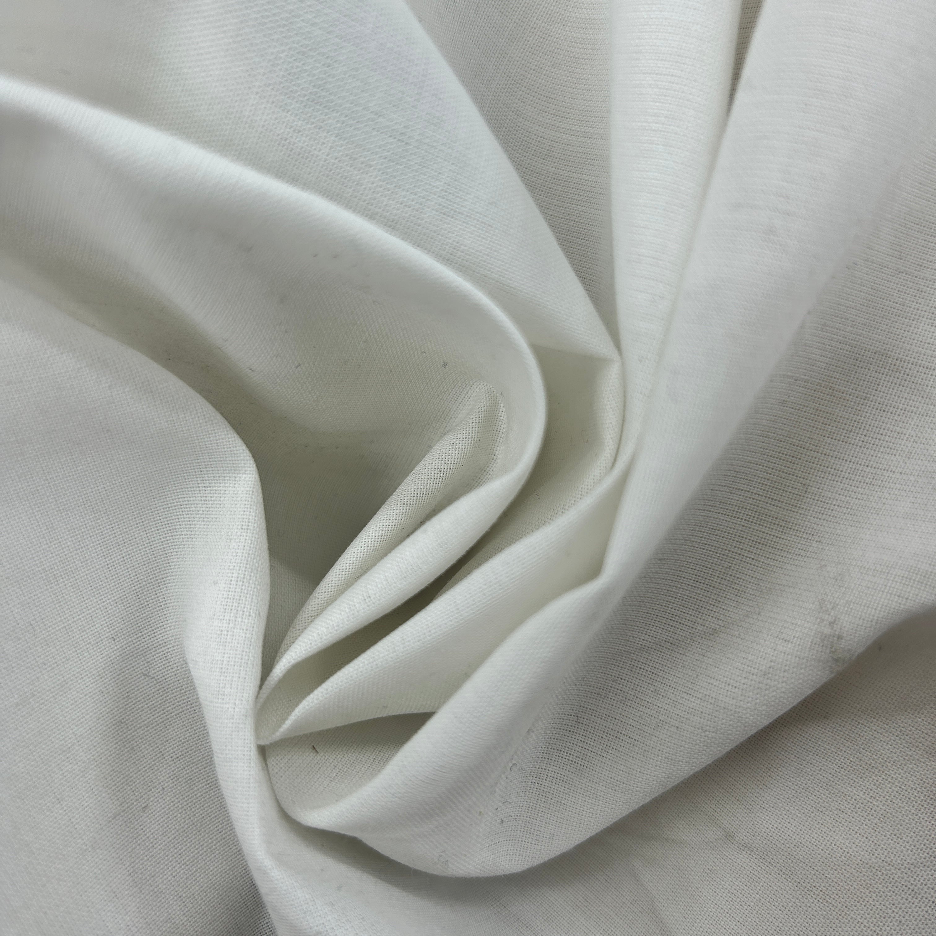 A close-up of draped off-white fabric with soft folds and a visible woven texture.