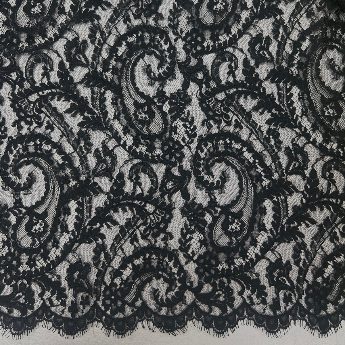 Black lace fabric with an intricate floral and scroll paisley pattern, shown in a close-up view.